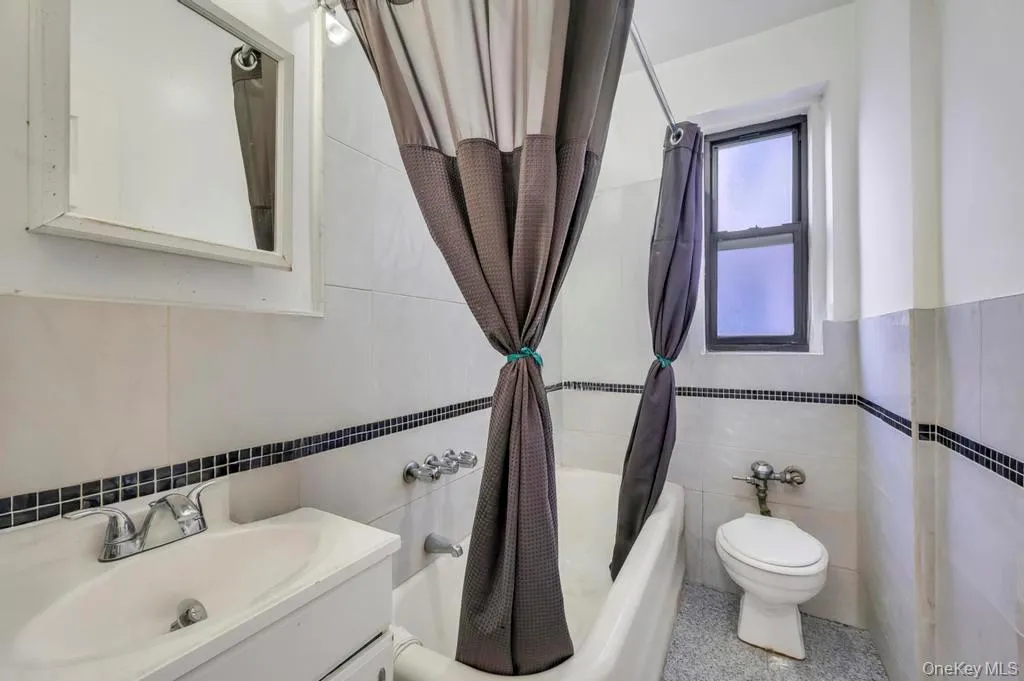 Bathroom with vanity, tile walls, and shower / tub combo with curtain Bathroom with vanity, tile walls, and shower / tub combo with curtain