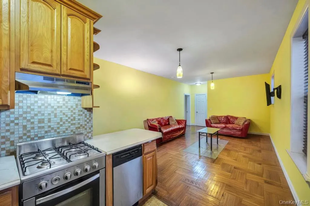 Kitchen with stainless steel appliances, light countertops, backsplash, under cabinet range hood, and brown cabinets Kitchen with stainless steel appliances, light countertops, backsplash, under cabinet range hood, and brown cabinets