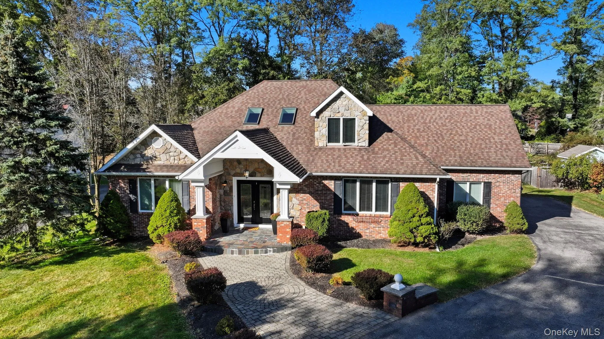 View of front facade featuring stone siding, a front lawn, brick siding, and roof with shingles View of front facade featuring stone siding, a front lawn, brick siding, and roof with shingles