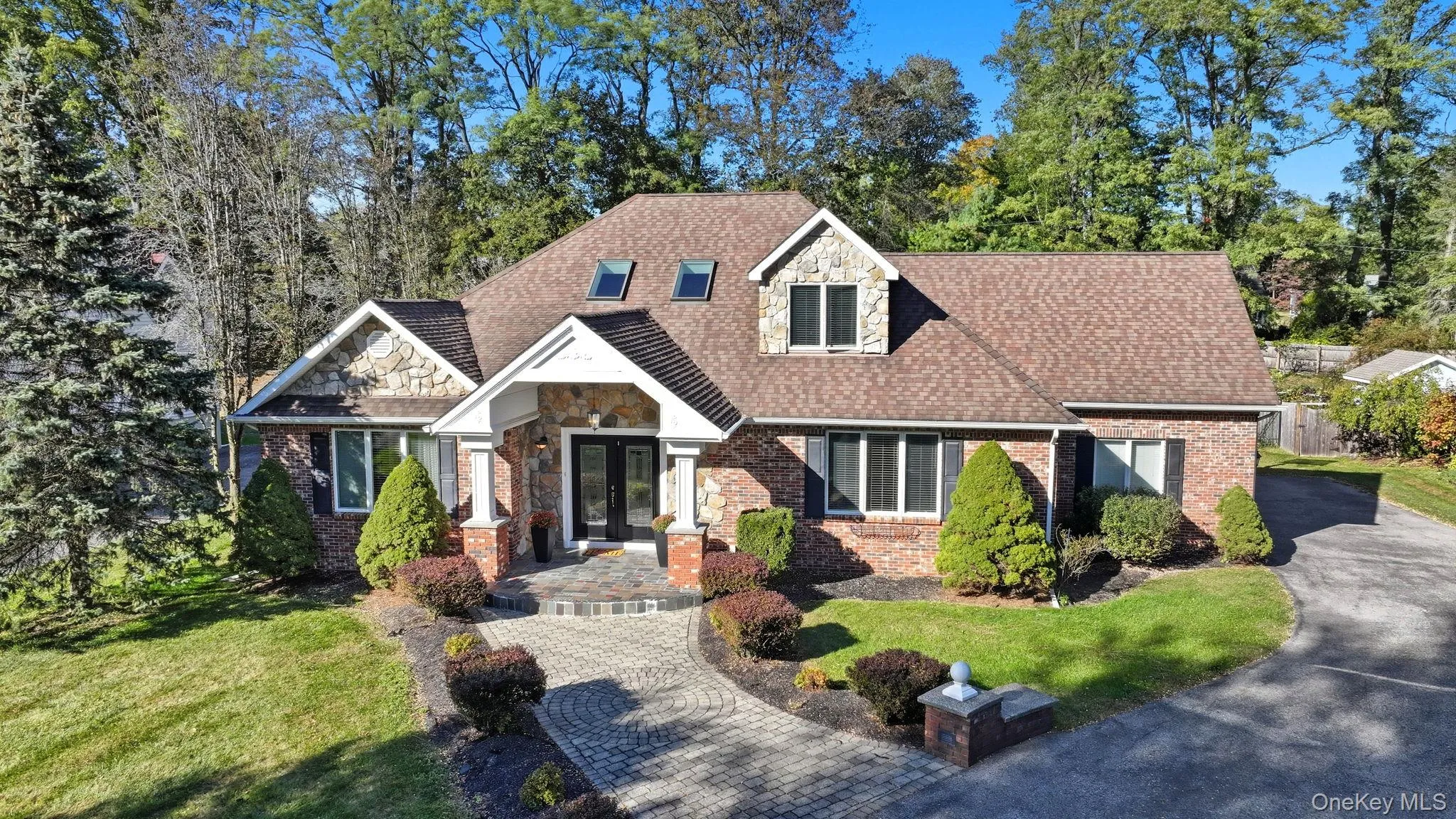 View of front of house featuring stone siding, a front yard, and brick siding View of front of house featuring stone siding, a front yard, and brick siding