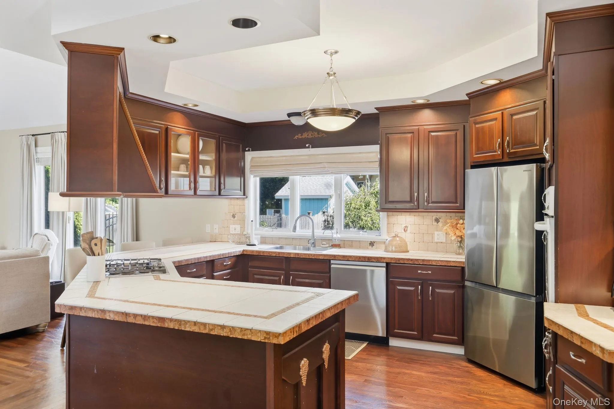 Kitchen with a peninsula, appliances with stainless steel finishes, glass insert cabinets, hanging light fixtures, and recessed lighting Kitchen with a peninsula, appliances with stainless steel finishes, glass insert cabinets, hanging light fixtures, and recessed lighting