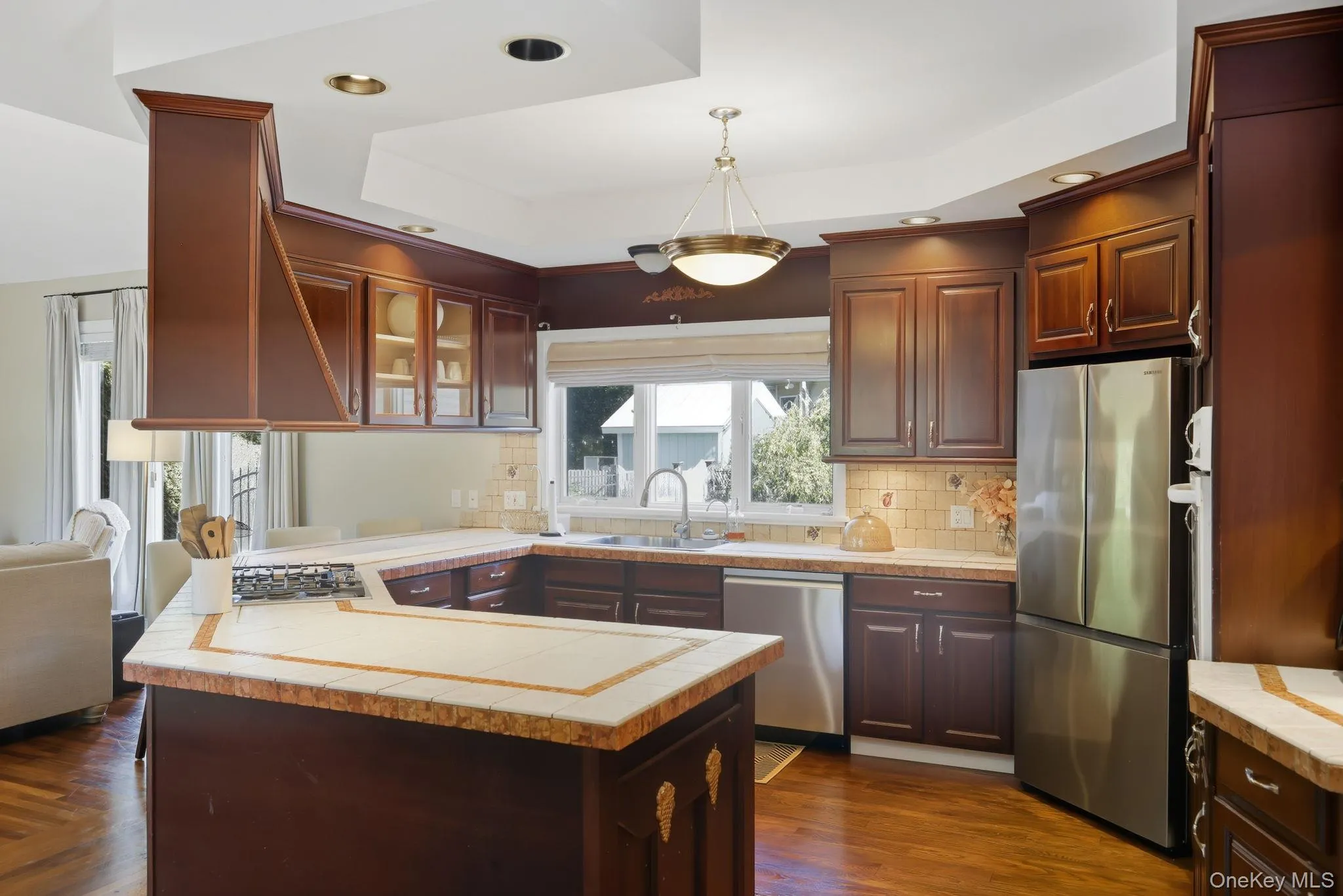 Kitchen with appliances with stainless steel finishes, a peninsula, a raised ceiling, tasteful backsplash, and recessed lighting Kitchen with appliances with stainless steel finishes, a peninsula, a raised ceiling, tasteful backsplash, and recessed lighting