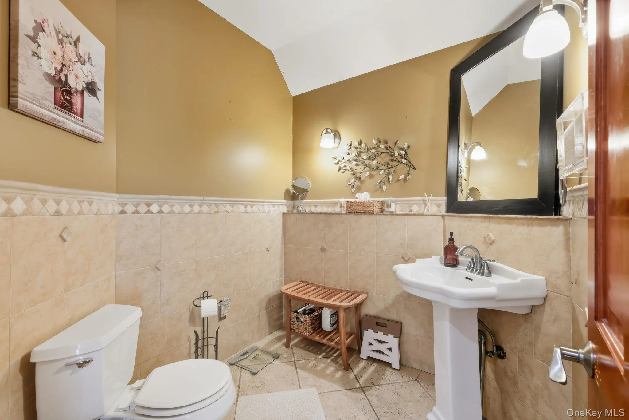 Bathroom with tile patterned floors, tile walls, lofted ceiling, and wainscoting Bathroom with tile patterned floors, tile walls, lofted ceiling, and wainscoting