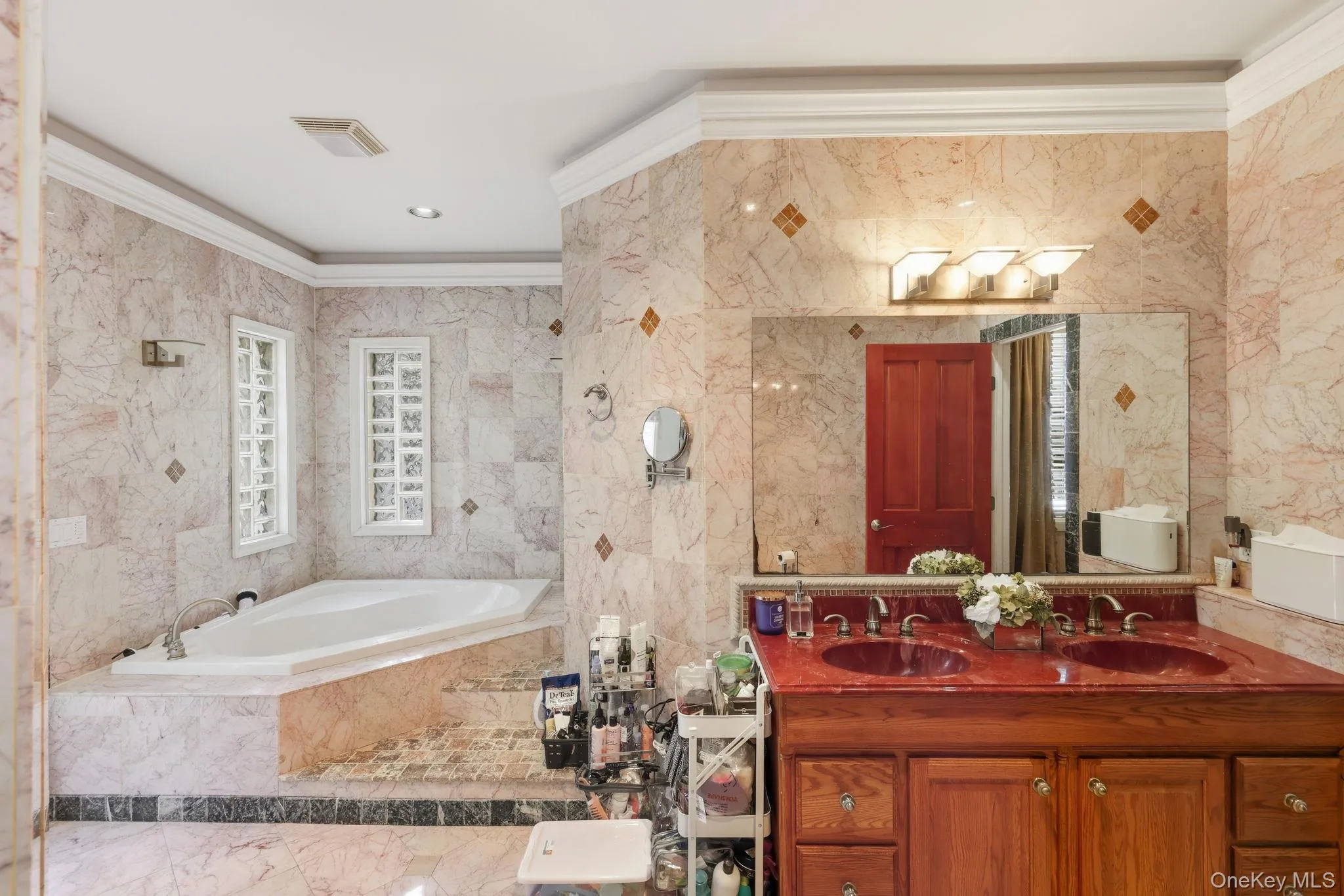 Bathroom with ornamental molding, tile walls, double vanity, a garden tub, and marble finish floors Bathroom with ornamental molding, tile walls, double vanity, a garden tub, and marble finish floors