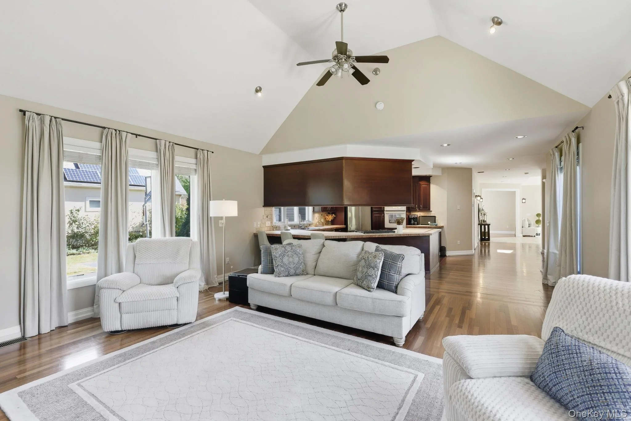 Living area featuring high vaulted ceiling, ceiling fan, dark wood-style floors, and recessed lighting Living area featuring high vaulted ceiling, ceiling fan, dark wood-style floors, and recessed lighting
