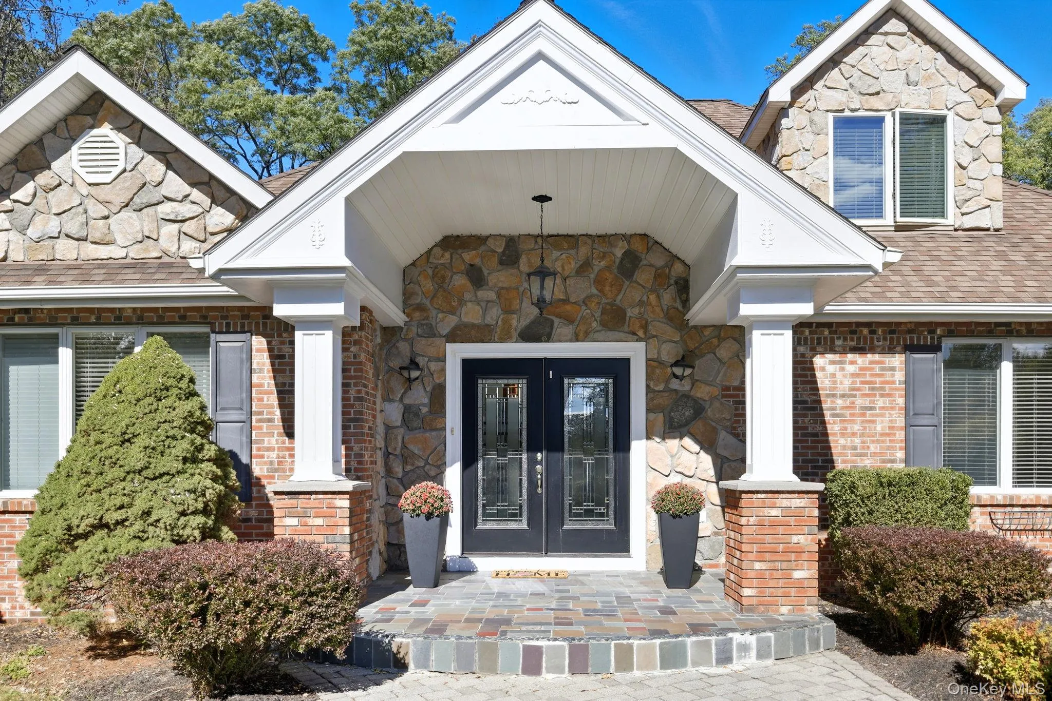 View of exterior entry with stone siding, roof with shingles, covered porch, and french doors View of exterior entry with stone siding, roof with shingles, covered porch, and french doors