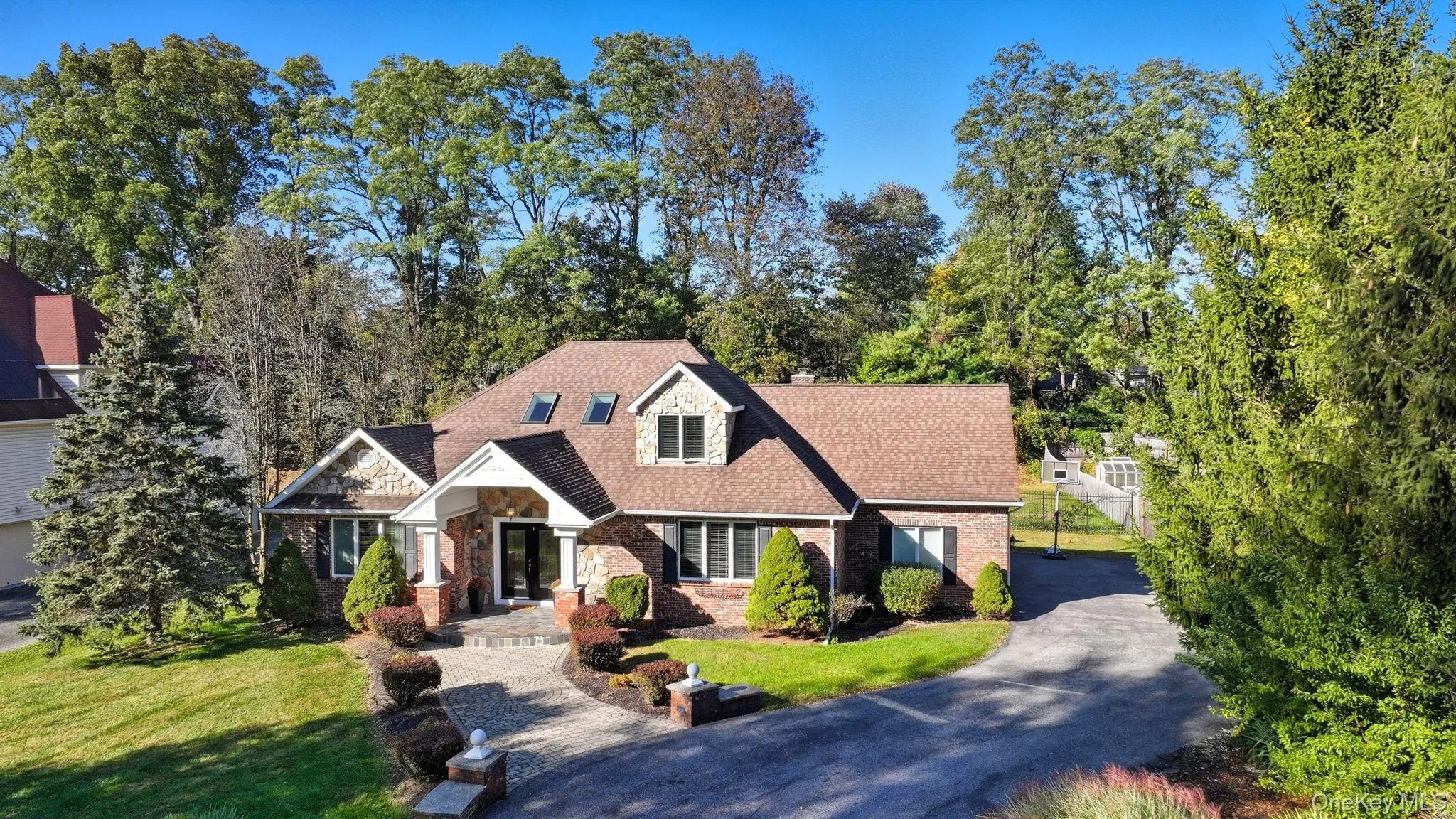 View of front of home with brick siding, stone siding, a front yard, and a shingled roof View of front of home with brick siding, stone siding, a front yard, and a shingled roof