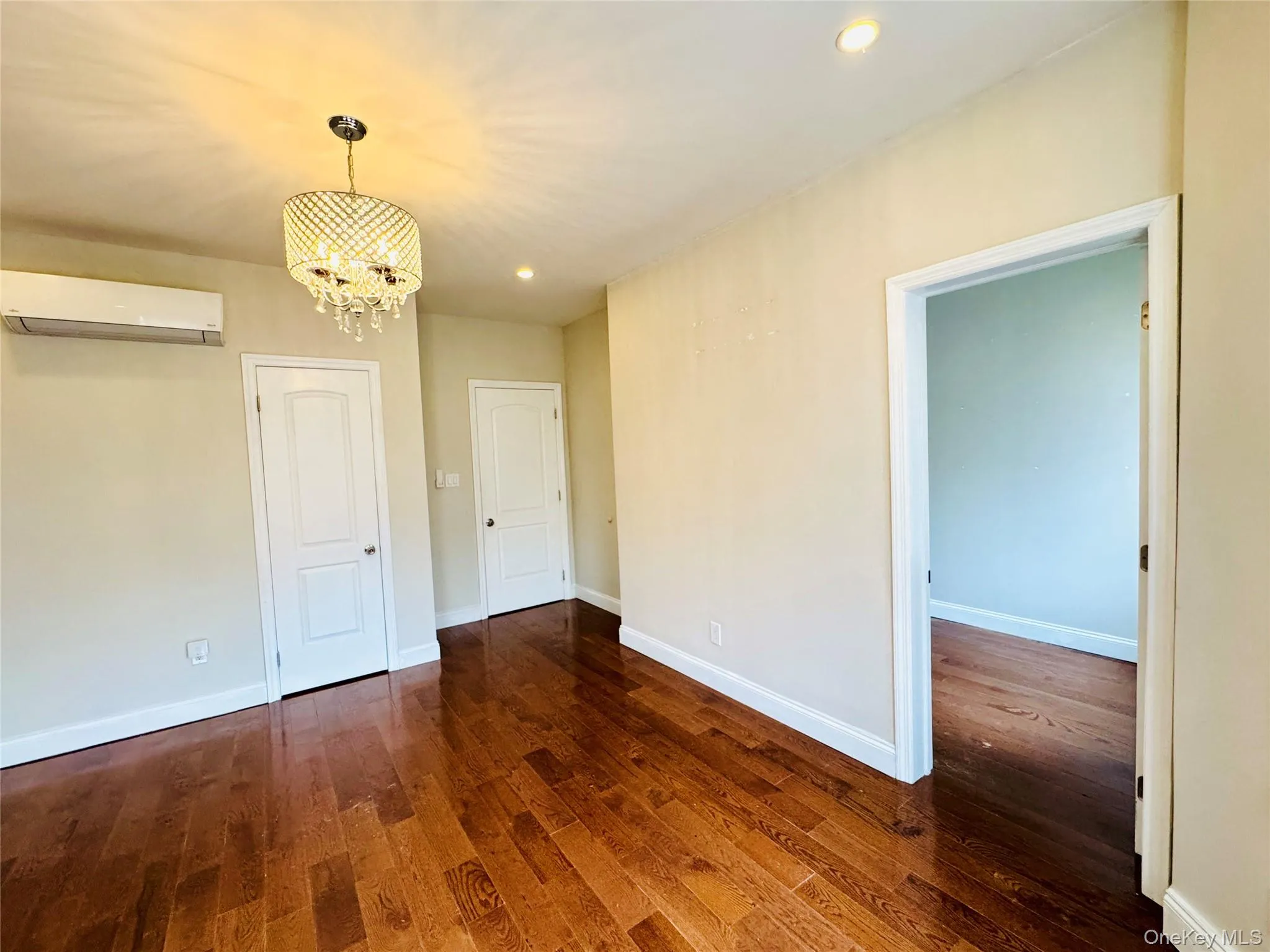 Unfurnished dining area featuring dark wood finished floors, recessed lighting, a chandelier, and a wall mounted air conditioner Unfurnished dining area featuring dark wood finished floors, recessed lighting, a chandelier, and a wall mounted air conditioner