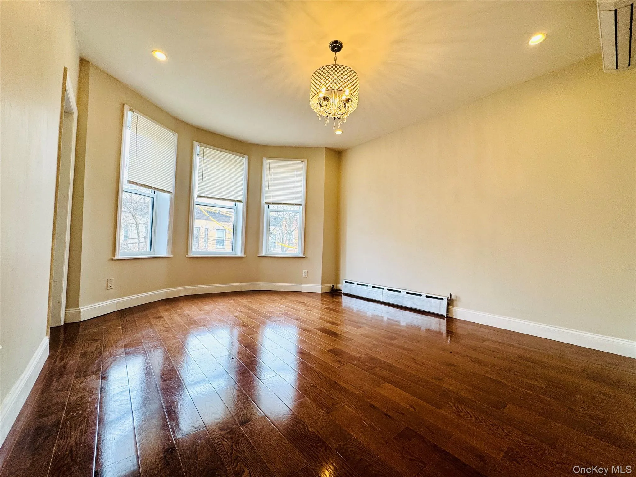 Unfurnished room featuring hardwood / wood-style flooring, recessed lighting, a chandelier, and a baseboard radiator Unfurnished room featuring hardwood / wood-style flooring, recessed lighting, a chandelier, and a baseboard radiator