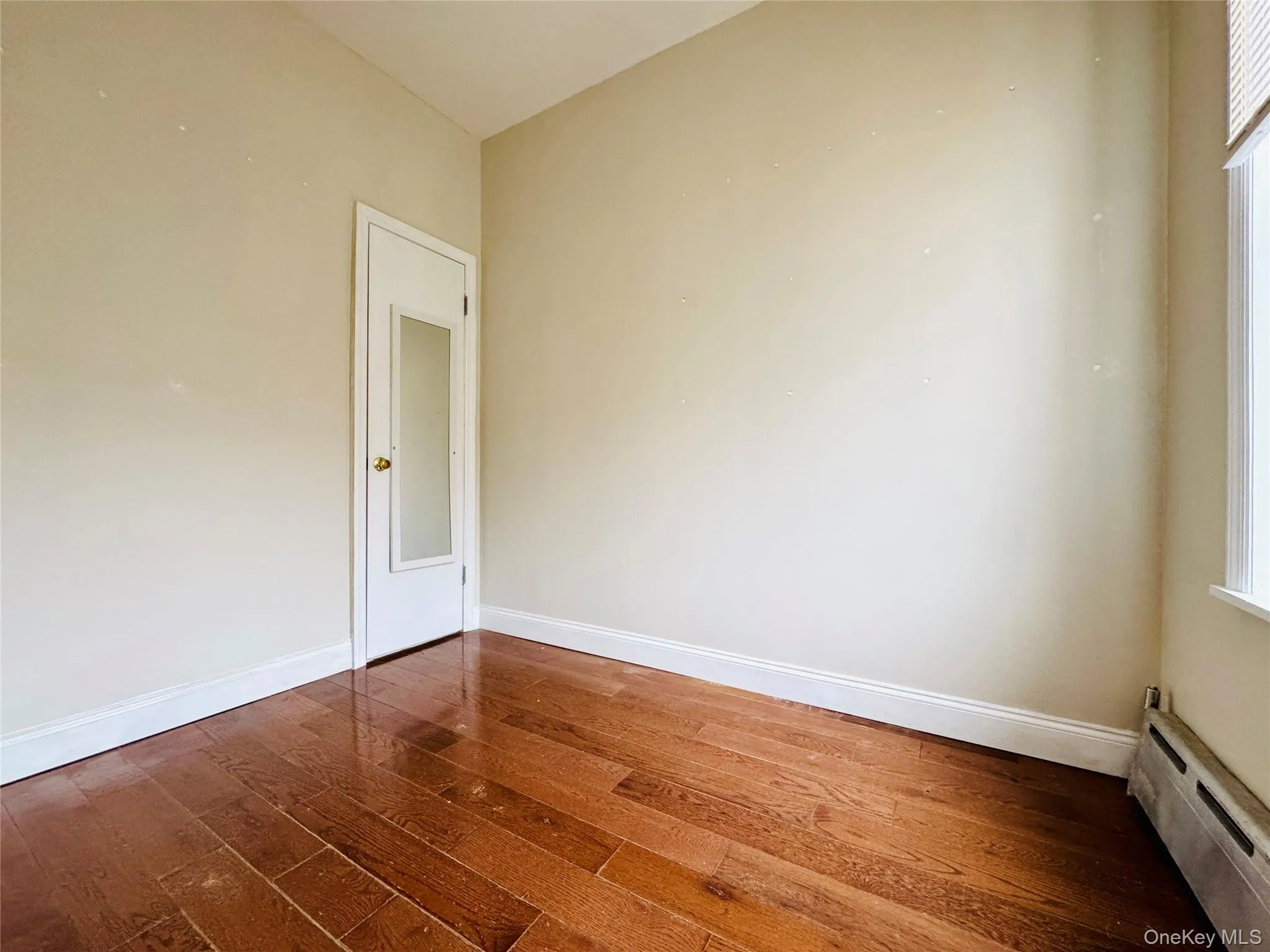 Unfurnished room featuring a baseboard heating unit and dark wood-type flooring Unfurnished room featuring a baseboard heating unit and dark wood-type flooring