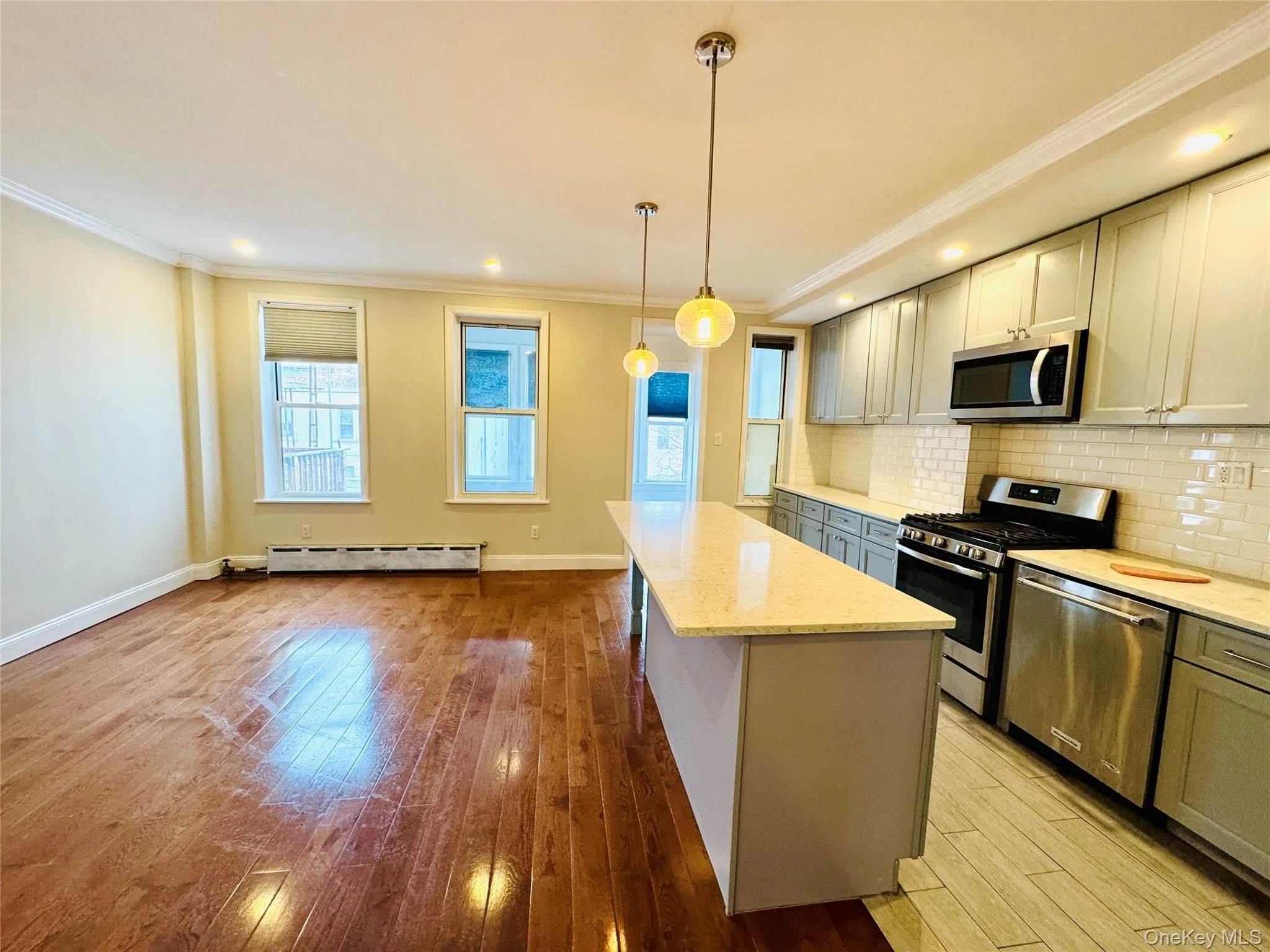 Kitchen featuring crown molding, gray cabinets, appliances with stainless steel finishes, tasteful backsplash, and a kitchen island Kitchen featuring crown molding, gray cabinets, appliances with stainless steel finishes, tasteful backsplash, and a kitchen island