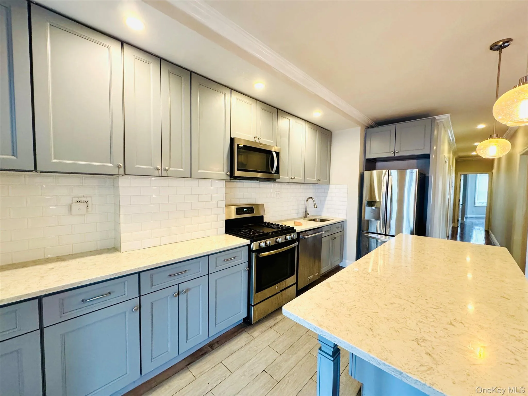Kitchen featuring appliances with stainless steel finishes, gray cabinets, light stone countertops, backsplash, and recessed lighting Kitchen featuring appliances with stainless steel finishes, gray cabinets, light stone countertops, backsplash, and recessed lighting