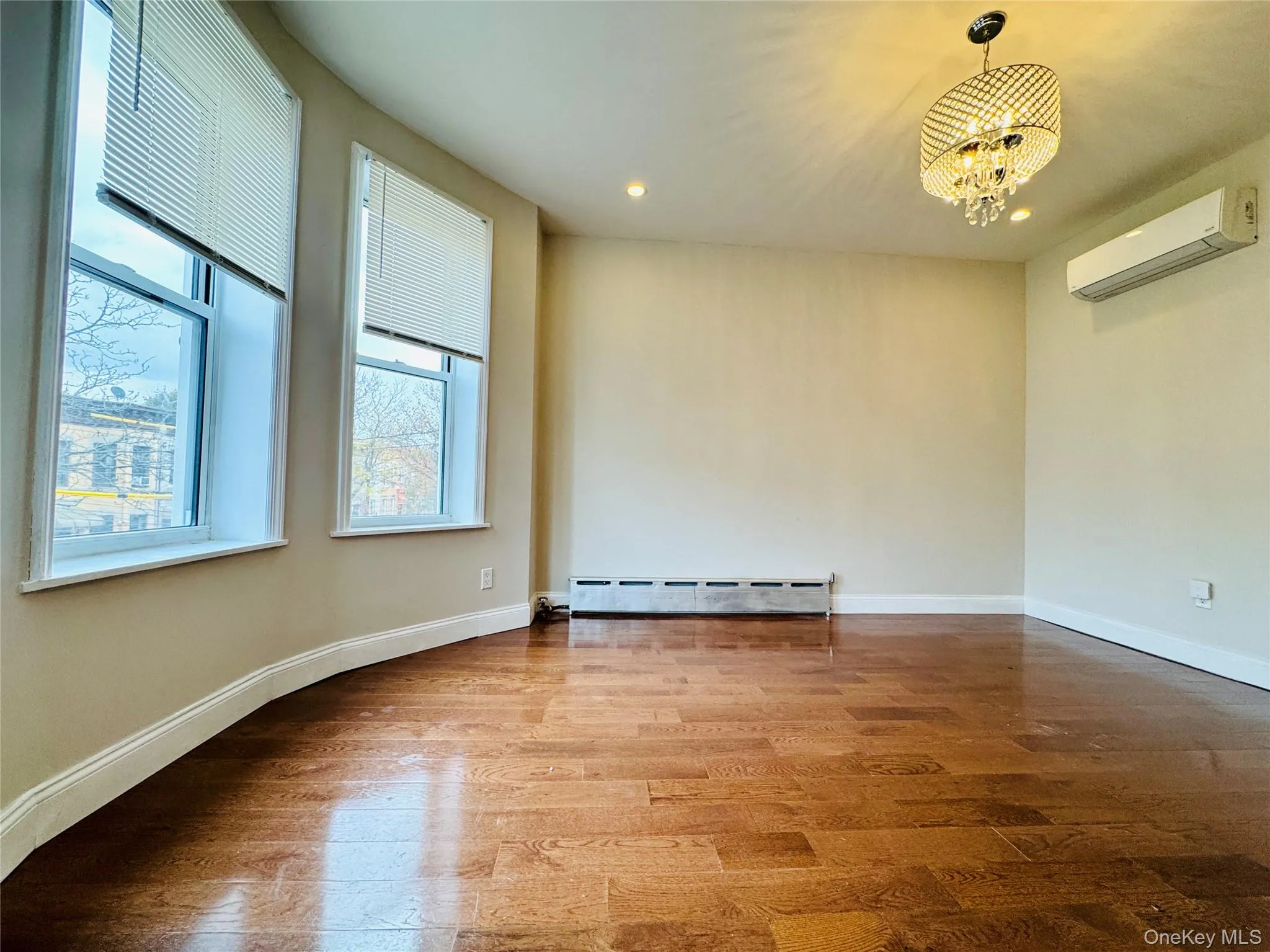 Spare room featuring wood finished floors, a wall mounted AC, a baseboard heating unit, a chandelier, and recessed lighting Spare room featuring wood finished floors, a wall mounted AC, a baseboard heating unit, a chandelier, and recessed lighting