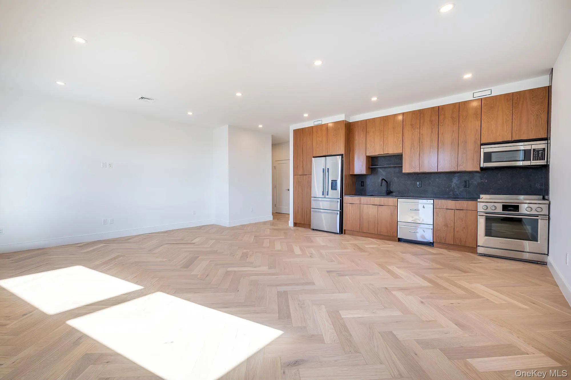 Kitchen with stainless steel appliances, recessed lighting, backsplash, dark countertops, and brown cabinetry Kitchen with stainless steel appliances, recessed lighting, backsplash, dark countertops, and brown cabinetry