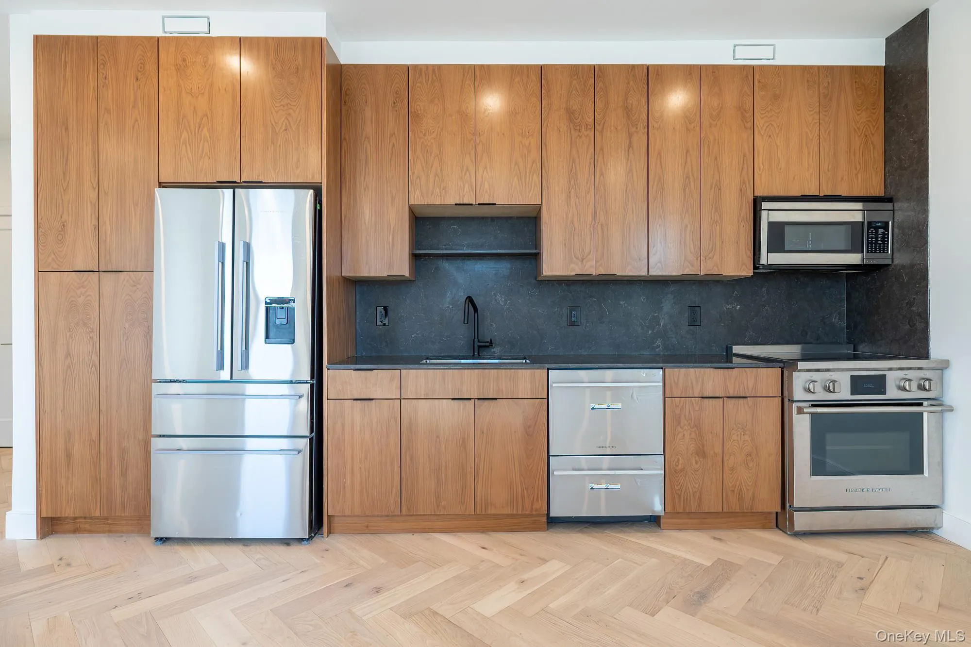Kitchen featuring stainless steel appliances, decorative backsplash, modern cabinets, and brown cabinetry Kitchen featuring stainless steel appliances, decorative backsplash, modern cabinets, and brown cabinetry