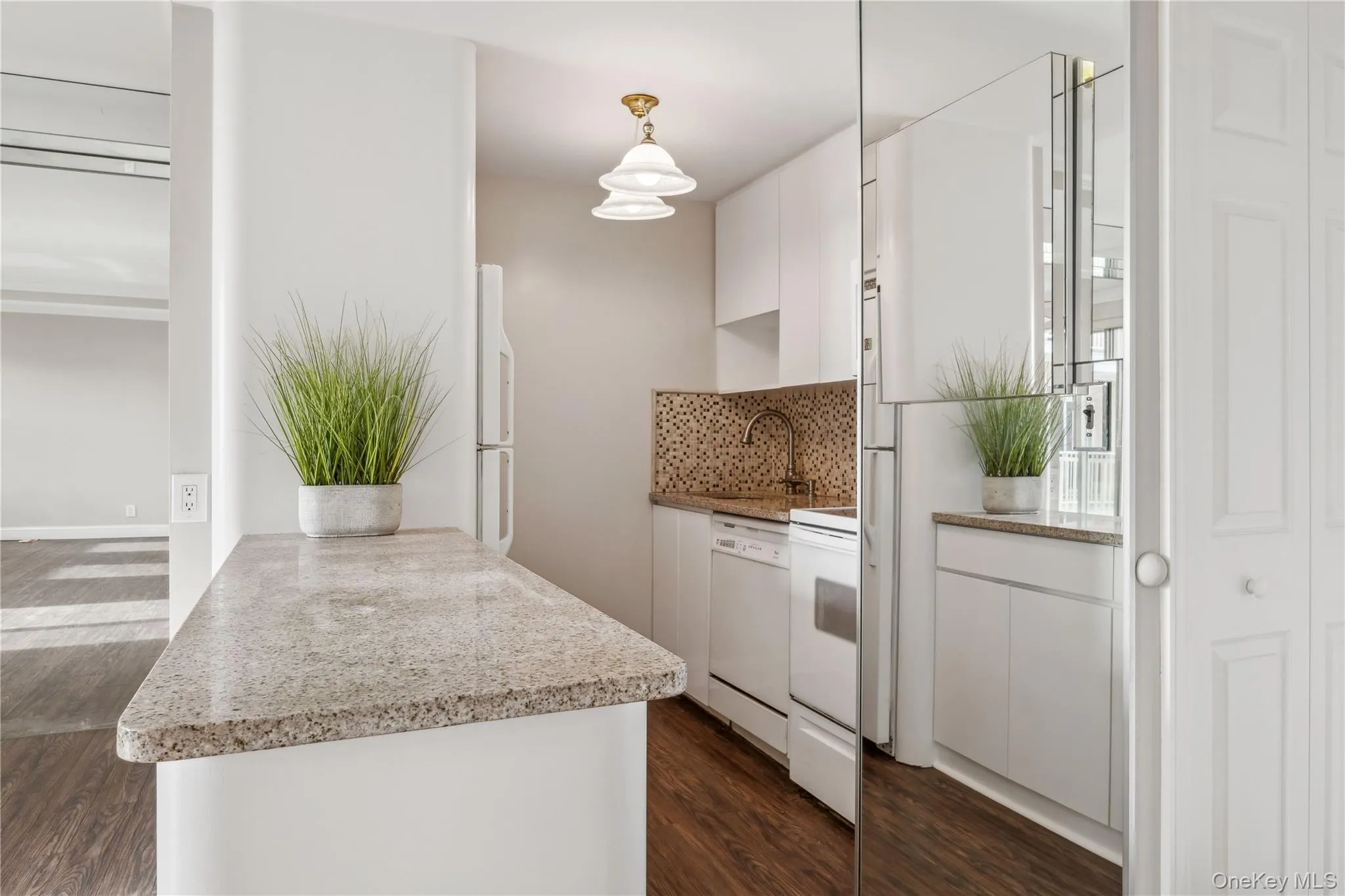 Kitchen with white cabinets, backsplash, white dishwasher, and kitchen peninsula Kitchen with white cabinets, backsplash, white dishwasher, and kitchen peninsula