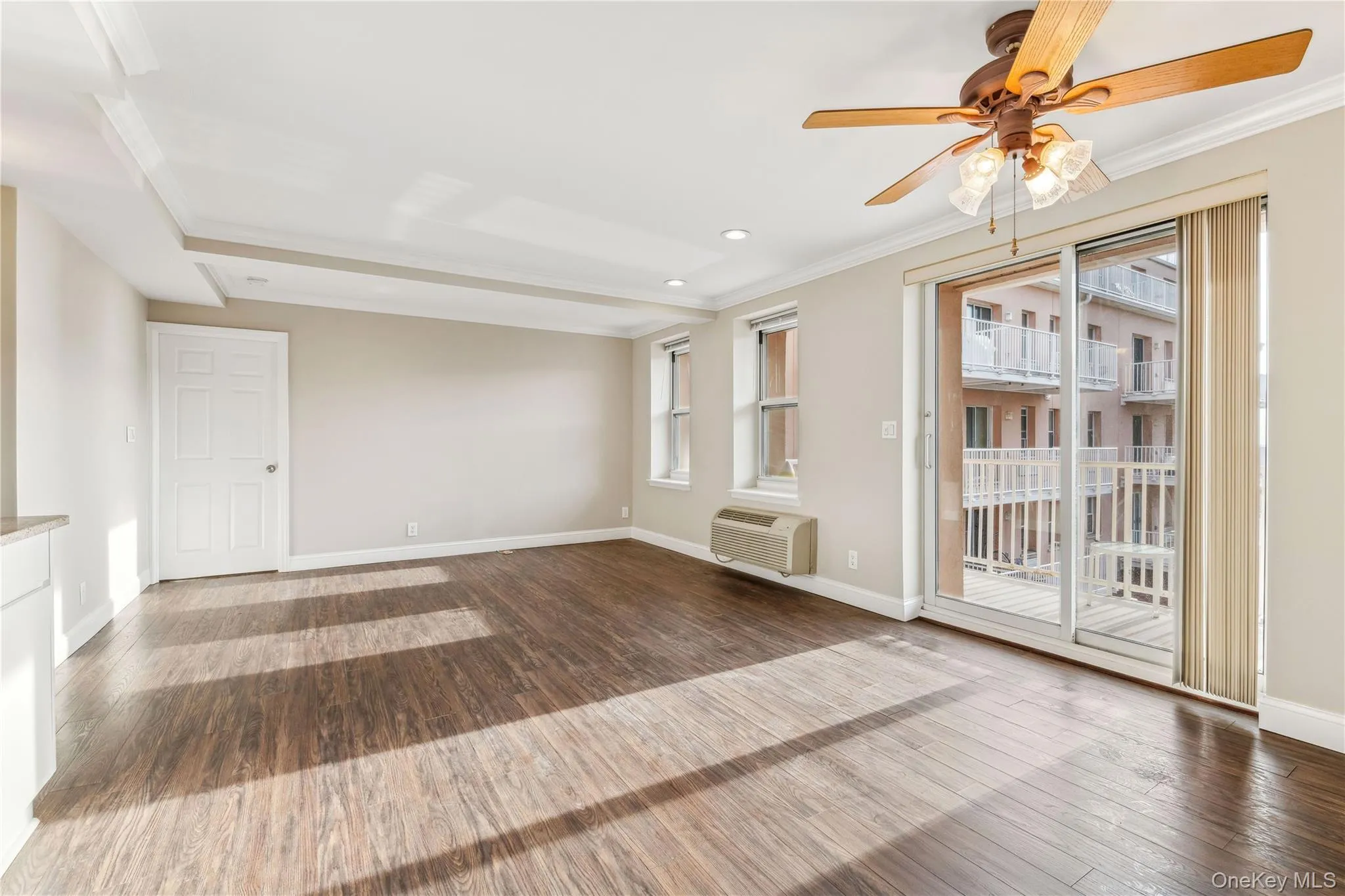 Spare room with wood-type flooring, an AC wall unit, a wealth of natural light, and crown molding Spare room with wood-type flooring, an AC wall unit, a wealth of natural light, and crown molding