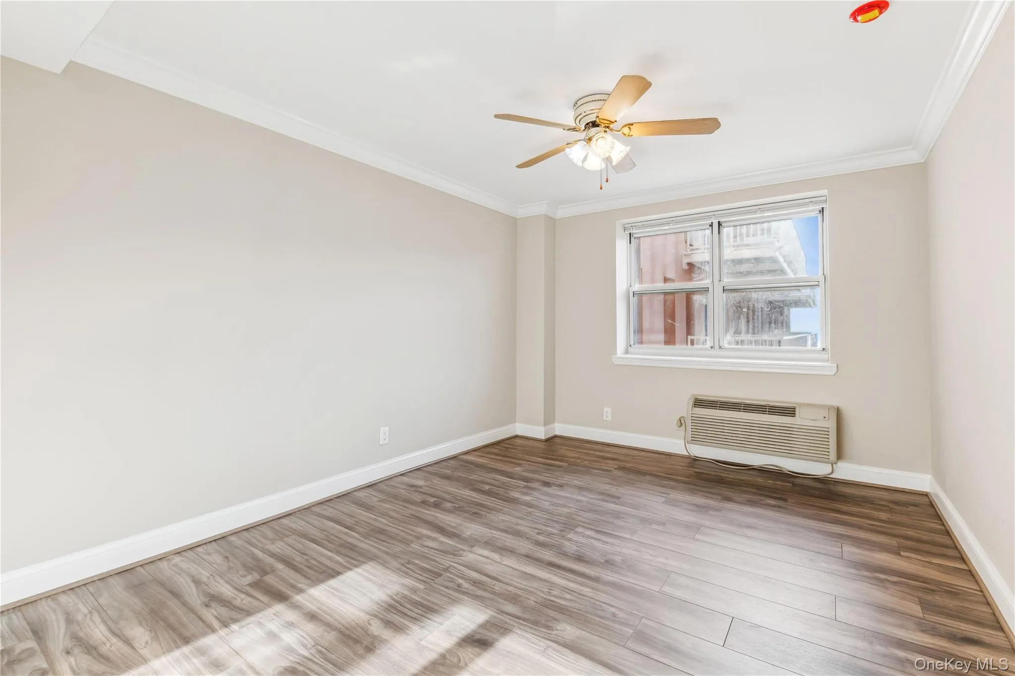 Spare room featuring hardwood / wood-style flooring, ceiling fan, ornamental molding, and a wall mounted AC Spare room featuring hardwood / wood-style flooring, ceiling fan, ornamental molding, and a wall mounted AC