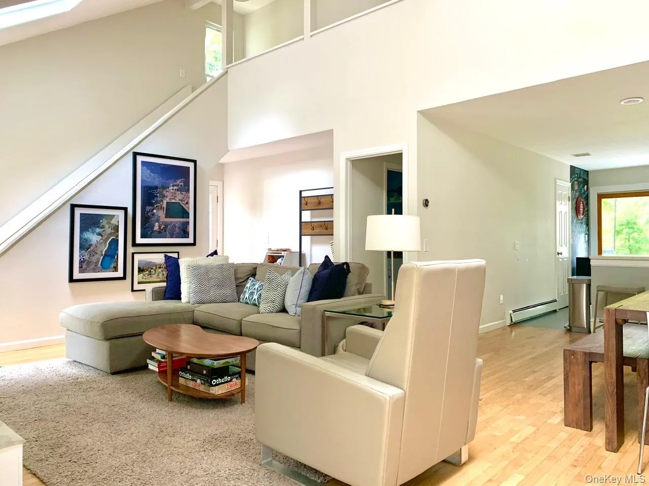 Living room with light wood-style floors, a baseboard radiator, and a towering ceiling Living room with light wood-style floors, a baseboard radiator, and a towering ceiling