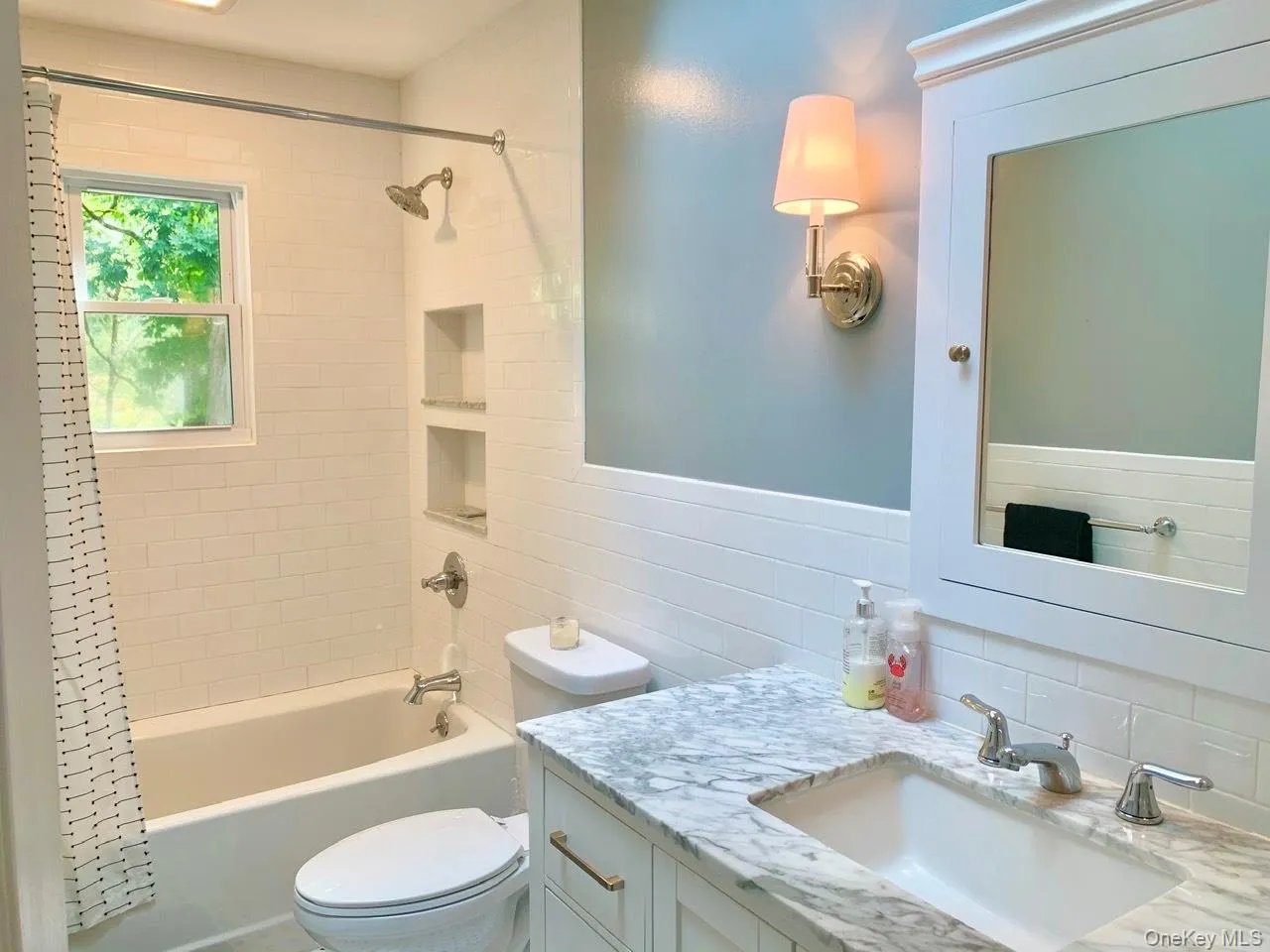 Bathroom featuring tasteful backsplash, shower / tub combo, vanity, and tile walls Bathroom featuring tasteful backsplash, shower / tub combo, vanity, and tile walls