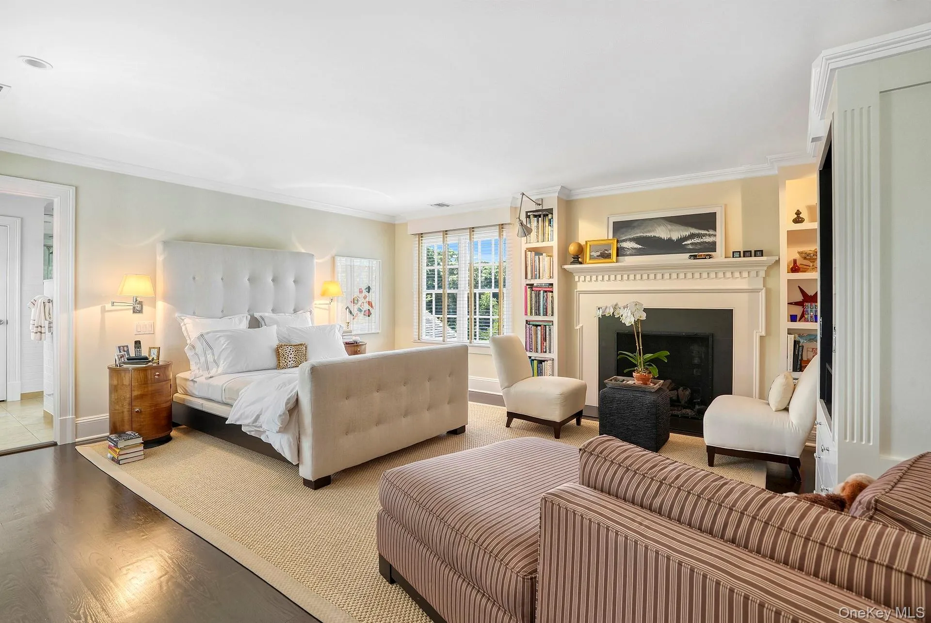 Bedroom with a fireplace, ornamental molding, and wood finished floors Bedroom with a fireplace, ornamental molding, and wood finished floors
