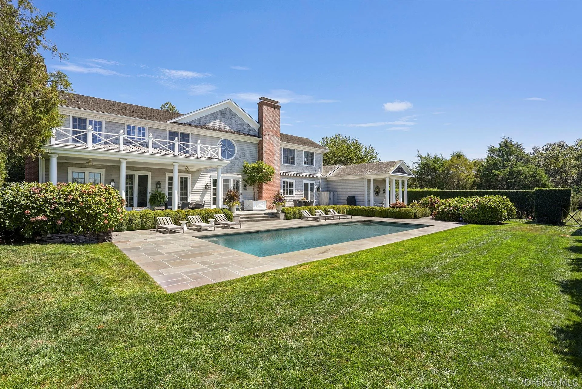 Rear view of property with a patio, a lawn, a chimney, an outdoor pool, and french doors Rear view of property with a patio, a lawn, a chimney, an outdoor pool, and french doors
