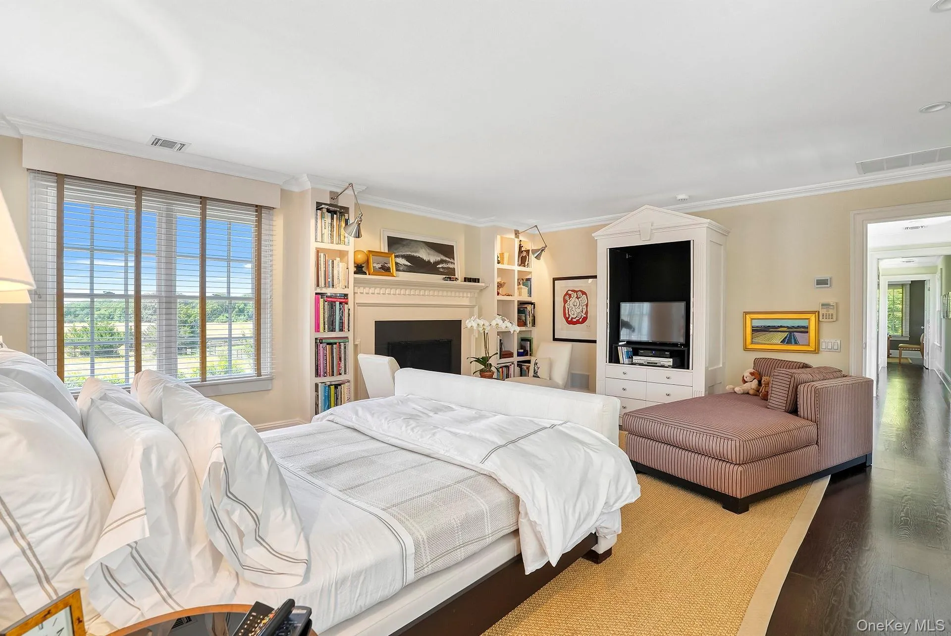 Bedroom with ornamental molding, wood finished floors, and a fireplace Bedroom with ornamental molding, wood finished floors, and a fireplace