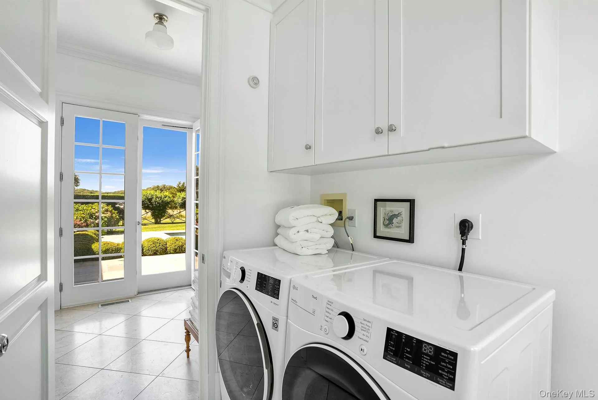 Laundry area featuring light tile patterned floors, washer and clothes dryer, ornamental molding, and cabinet space Laundry area featuring light tile patterned floors, washer and clothes dryer, ornamental molding, and cabinet space