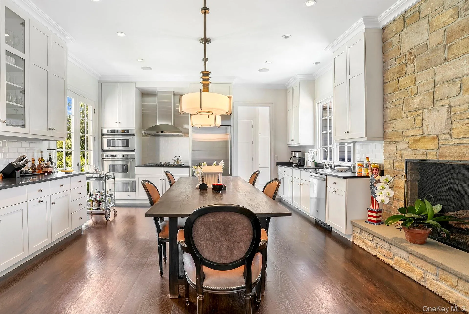 Dining room featuring crown molding, dark wood-style floors, a stone fireplace, and recessed lighting Dining room featuring crown molding, dark wood-style floors, a stone fireplace, and recessed lighting