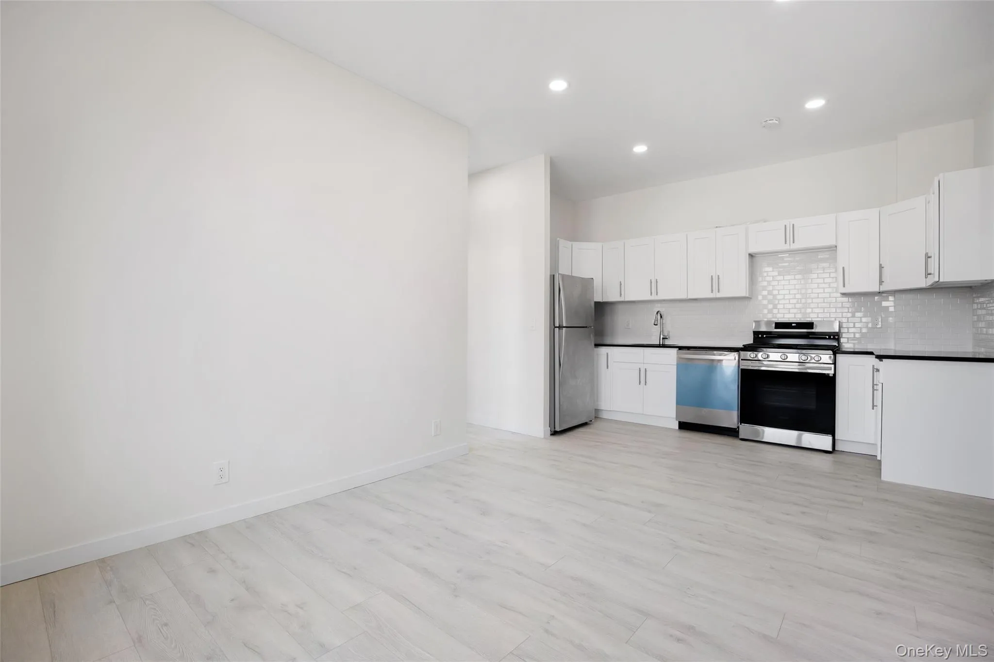 Kitchen featuring dark countertops, stainless steel appliances, decorative backsplash, white cabinetry, and recessed lighting Kitchen featuring dark countertops, stainless steel appliances, decorative backsplash, white cabinetry, and recessed lighting