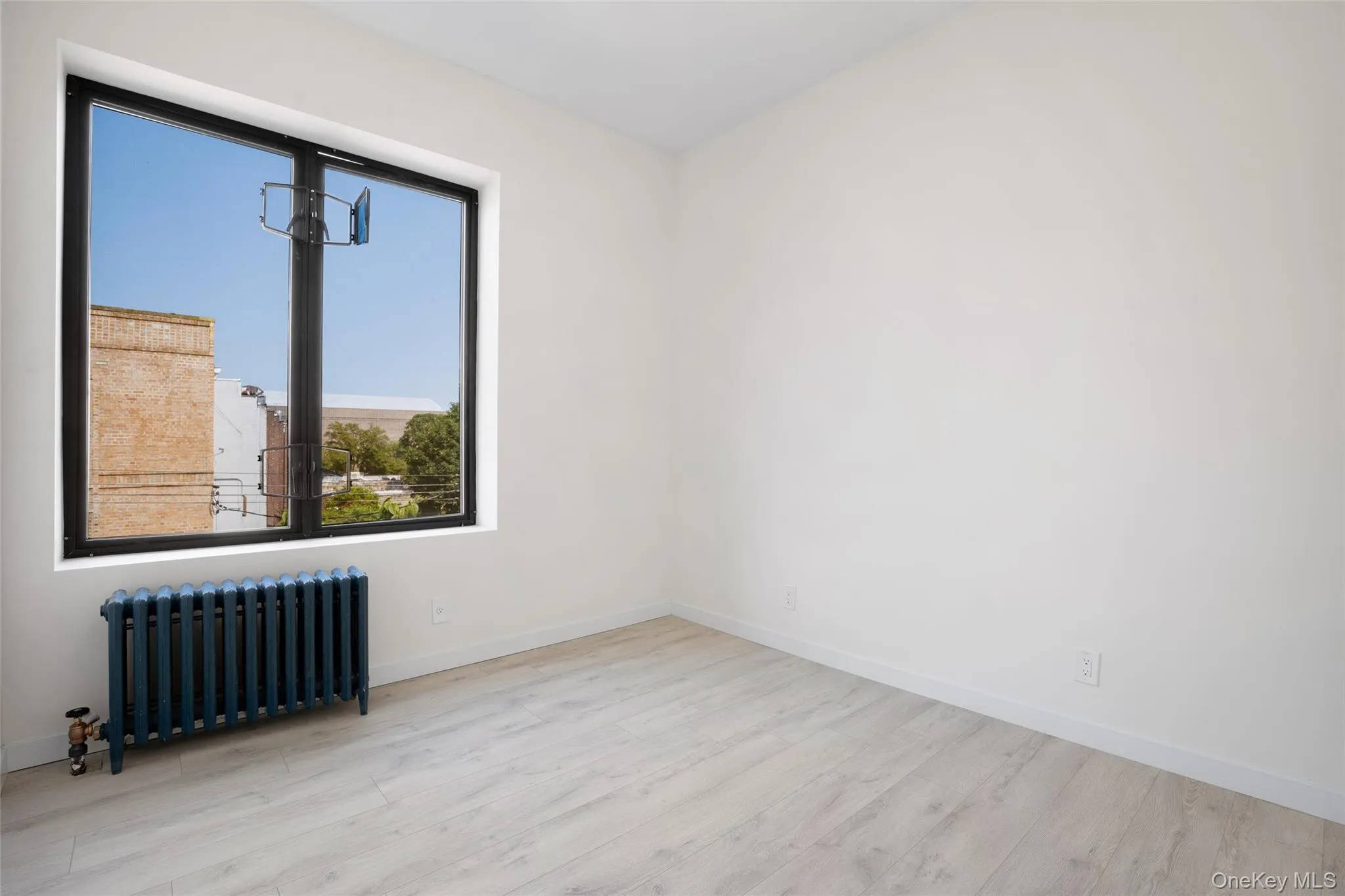 Unfurnished room featuring radiator heating unit and wood finished floors Unfurnished room featuring radiator heating unit and wood finished floors