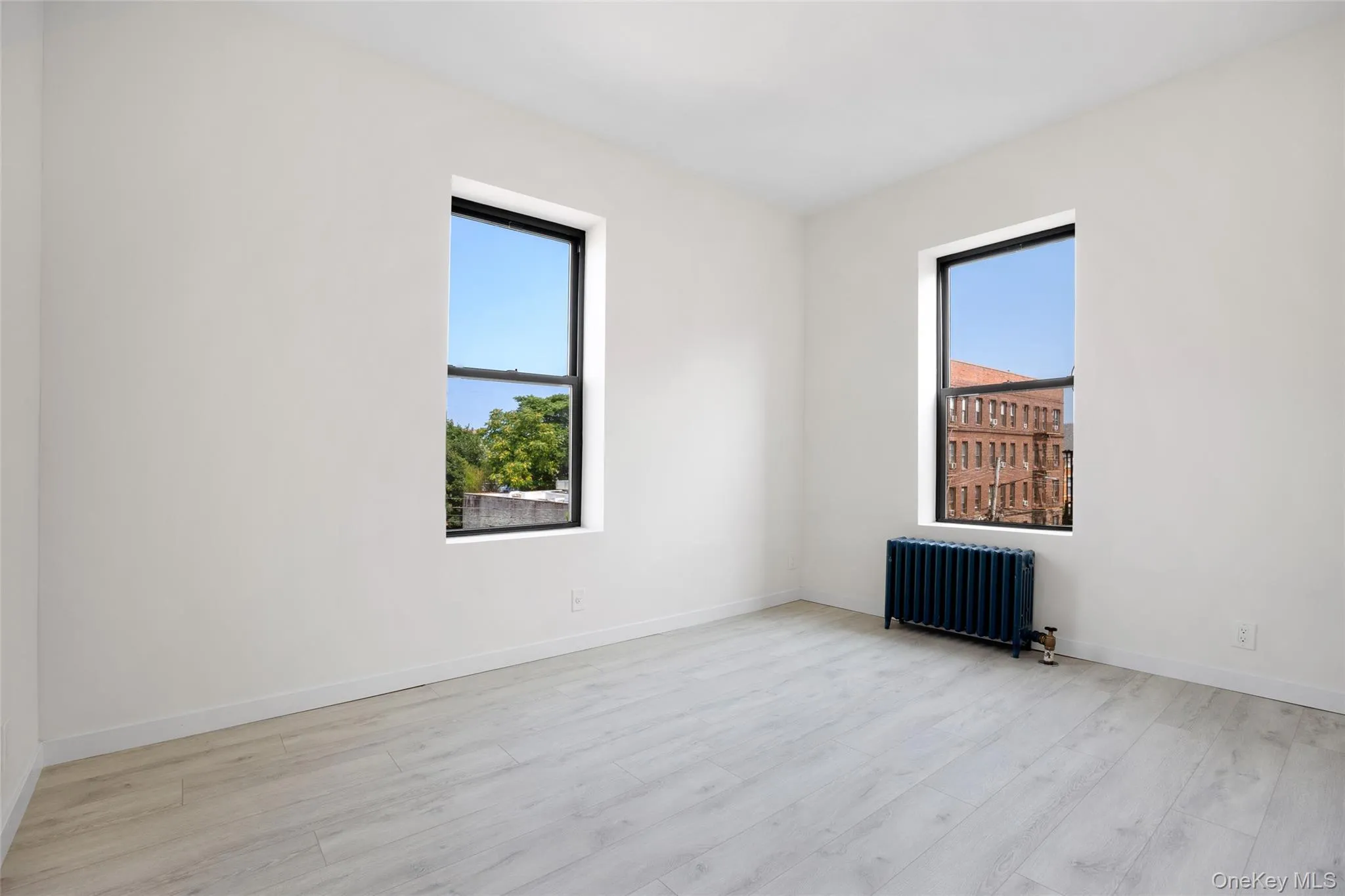 Unfurnished room with radiator heating unit and light wood-type flooring Unfurnished room with radiator heating unit and light wood-type flooring