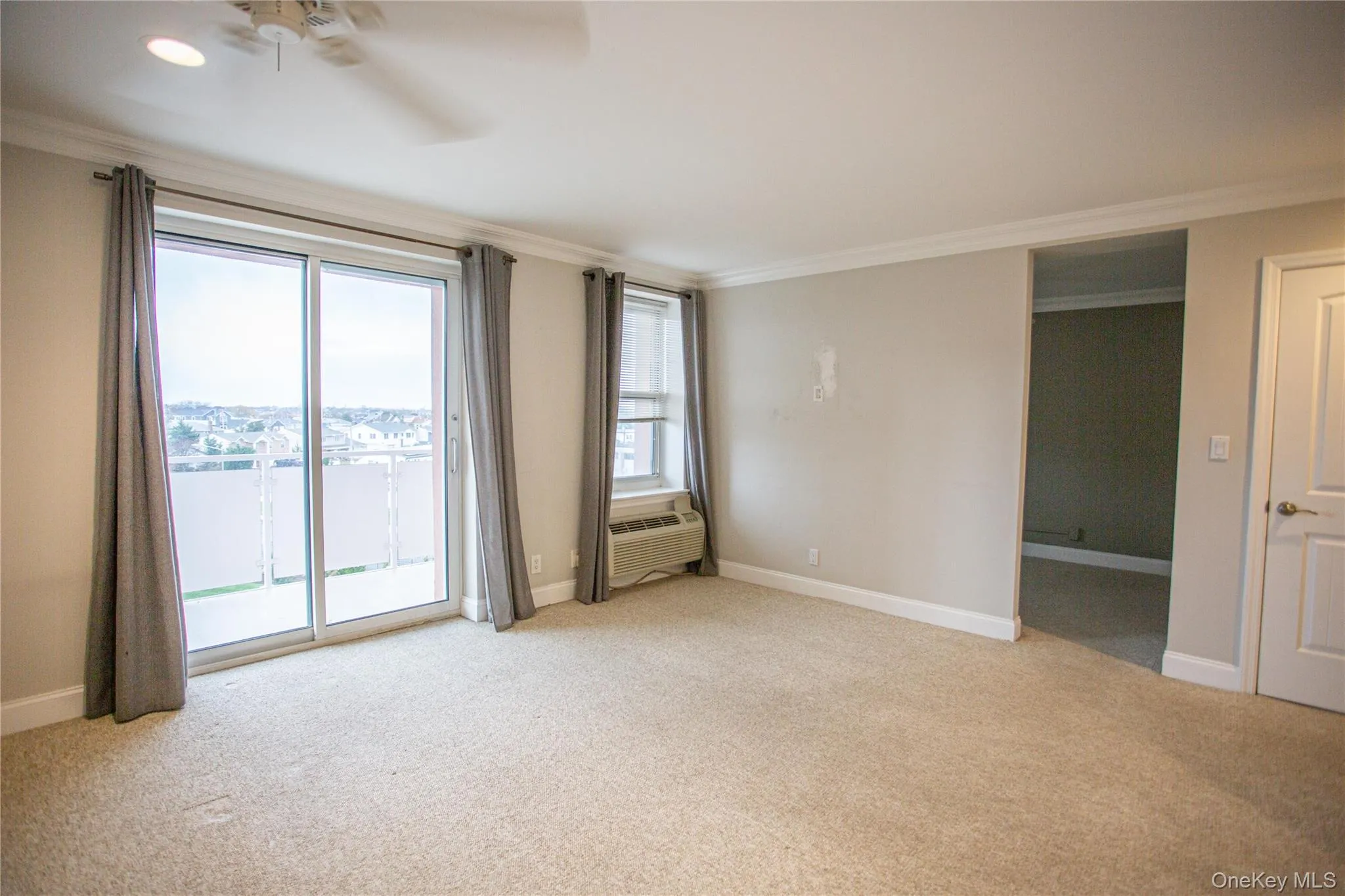 Spare room with ornamental molding, light carpet, a ceiling fan, and a wall mounted air conditioner Spare room with ornamental molding, light carpet, a ceiling fan, and a wall mounted air conditioner