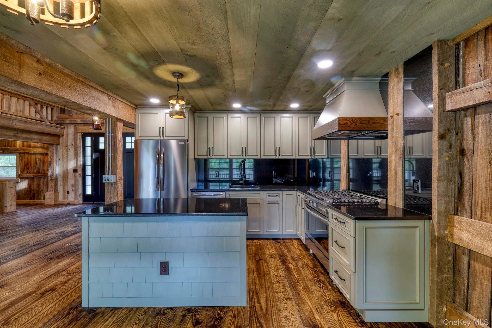 Kitchen featuring custom range hood, appliances with stainless steel finishes, decorative light fixtures, dark wood finished floors, and a center island Kitchen featuring custom range hood, appliances with stainless steel finishes, decorative light fixtures, dark wood finished floors, and a center island