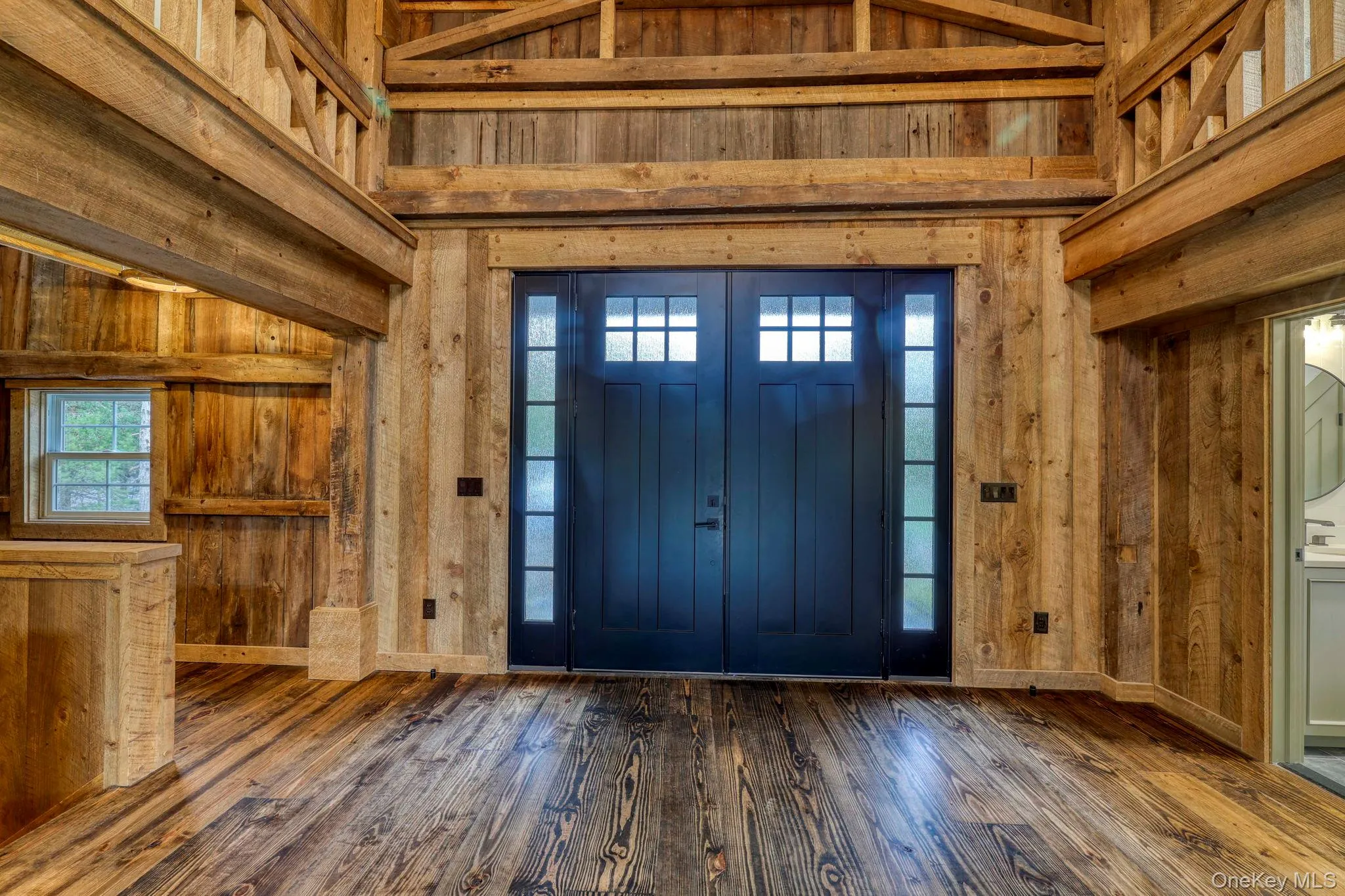 Foyer with wood walls, healthy amount of natural light, hardwood / wood-style floors, and high vaulted ceiling Foyer with wood walls, healthy amount of natural light, hardwood / wood-style floors, and high vaulted ceiling