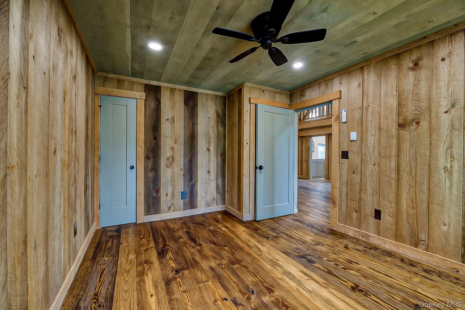 Empty room with wood walls, dark wood finished floors, ceiling fan, recessed lighting, and wooden ceiling Empty room with wood walls, dark wood finished floors, ceiling fan, recessed lighting, and wooden ceiling