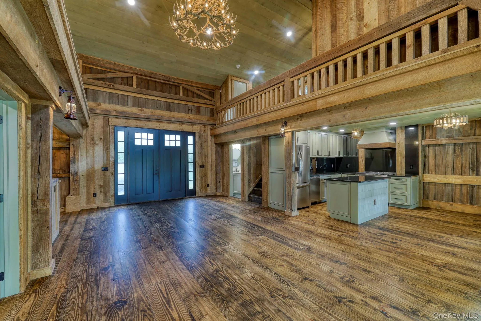 Entrance foyer with high vaulted ceiling, wood walls, dark wood-type flooring, wooden ceiling, and stairs Entrance foyer with high vaulted ceiling, wood walls, dark wood-type flooring, wooden ceiling, and stairs