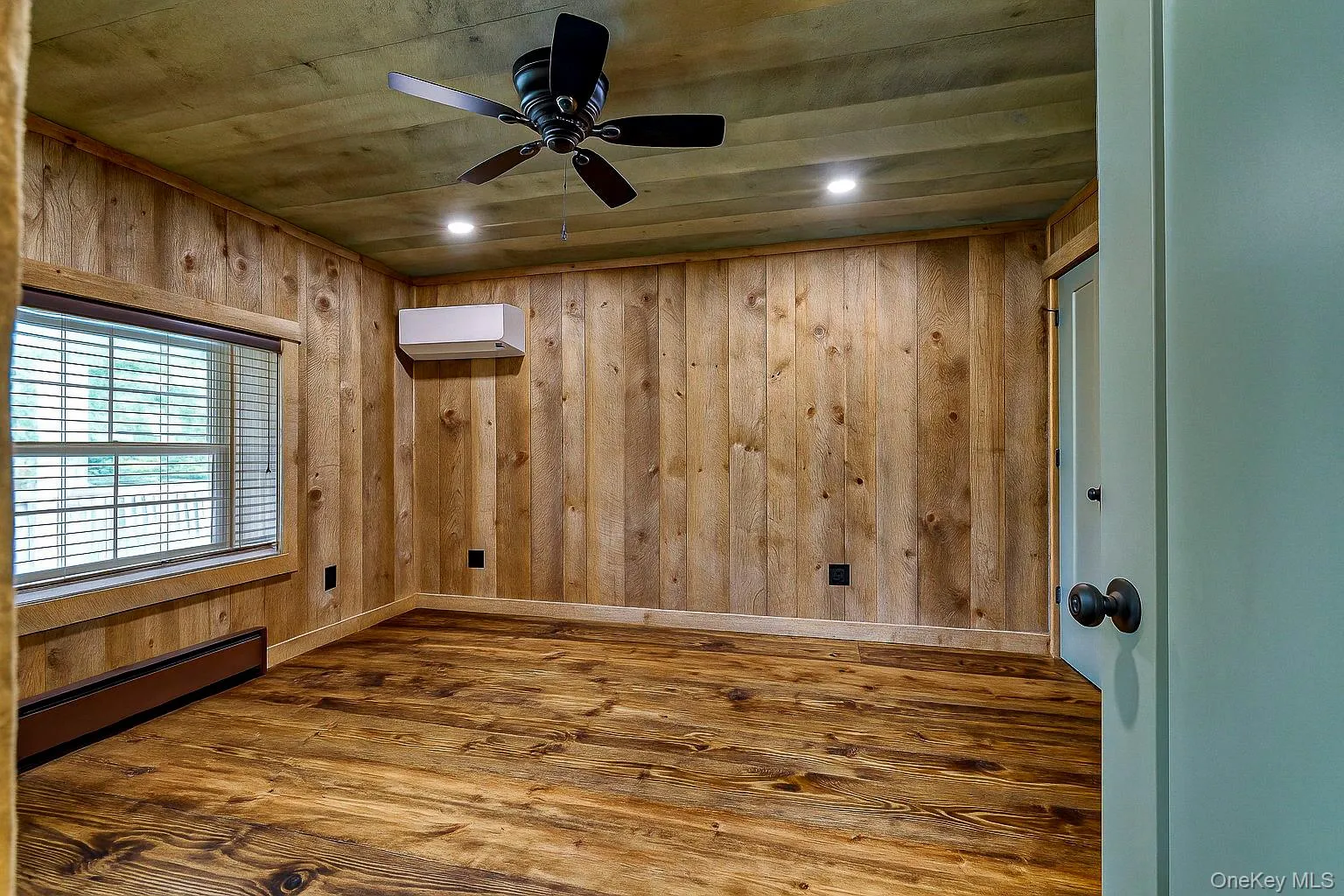 Unfurnished room featuring dark wood-type flooring, baseboard heating, wood walls, recessed lighting, and a ceiling fan Unfurnished room featuring dark wood-type flooring, baseboard heating, wood walls, recessed lighting, and a ceiling fan