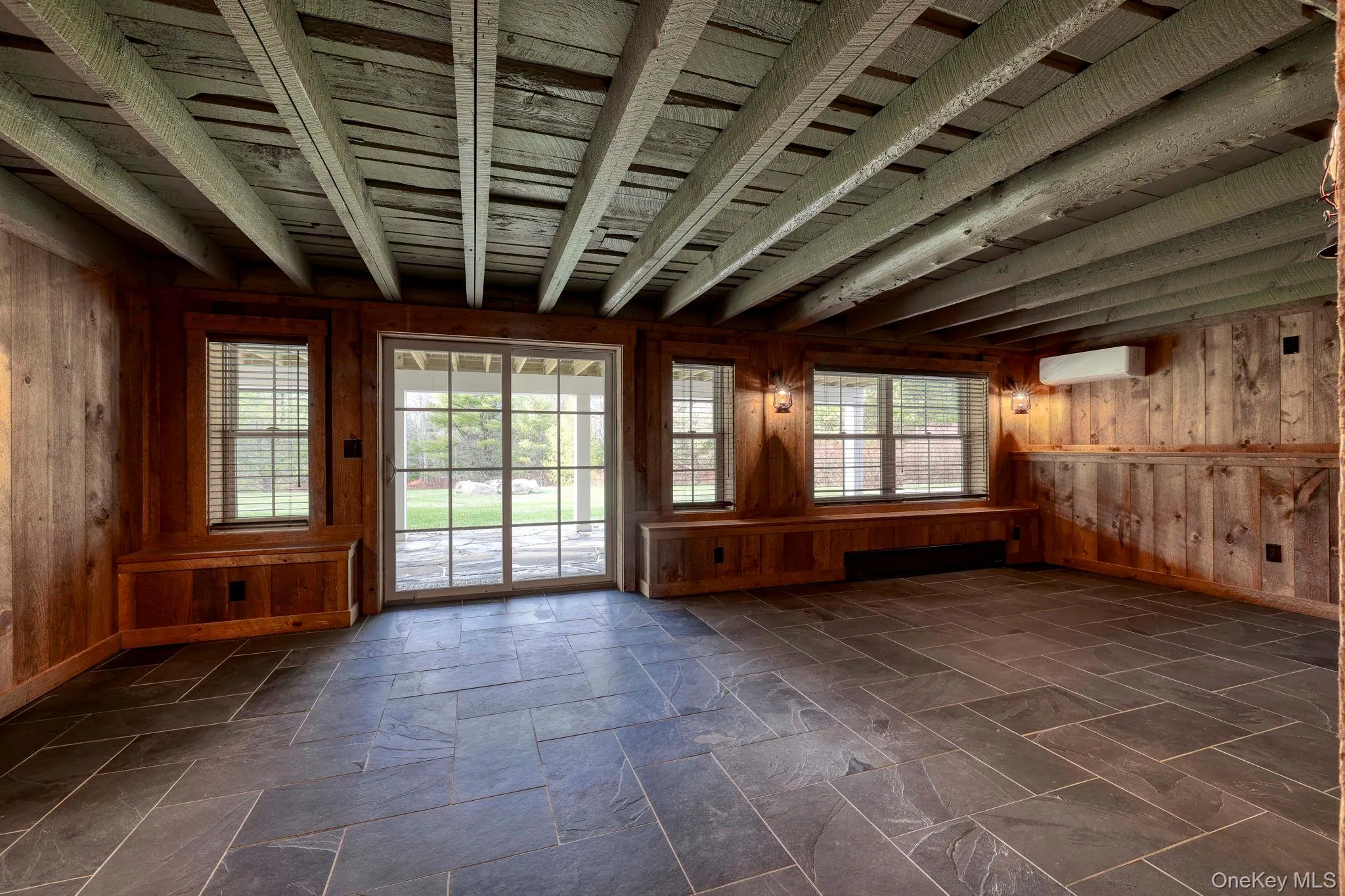 Unfurnished room featuring wooden walls, a wall unit AC, a baseboard radiator, and beam ceiling Unfurnished room featuring wooden walls, a wall unit AC, a baseboard radiator, and beam ceiling