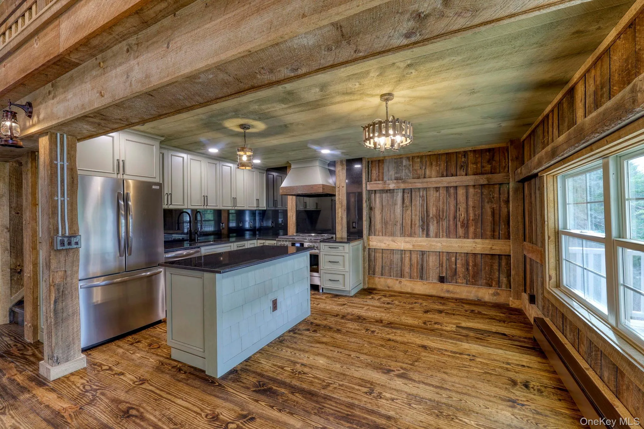 Kitchen with baseboard heating, pendant lighting, stainless steel appliances, dark wood finished floors, and wooden walls Kitchen with baseboard heating, pendant lighting, stainless steel appliances, dark wood finished floors, and wooden walls