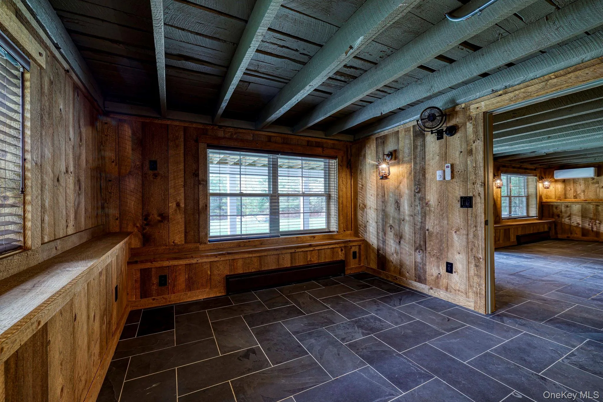 Spare room with wooden walls, beam ceiling, healthy amount of natural light, and baseboard heating Spare room with wooden walls, beam ceiling, healthy amount of natural light, and baseboard heating