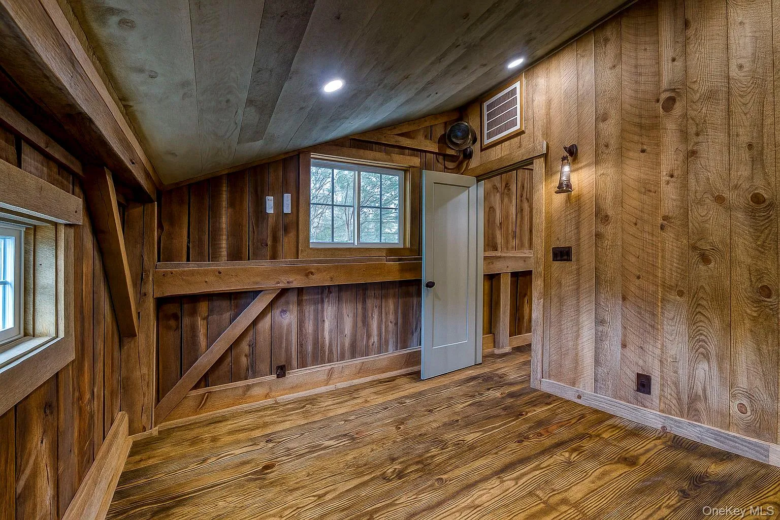 Unfurnished room with wooden walls, lofted ceiling, wood finished floors, and recessed lighting Unfurnished room with wooden walls, lofted ceiling, wood finished floors, and recessed lighting