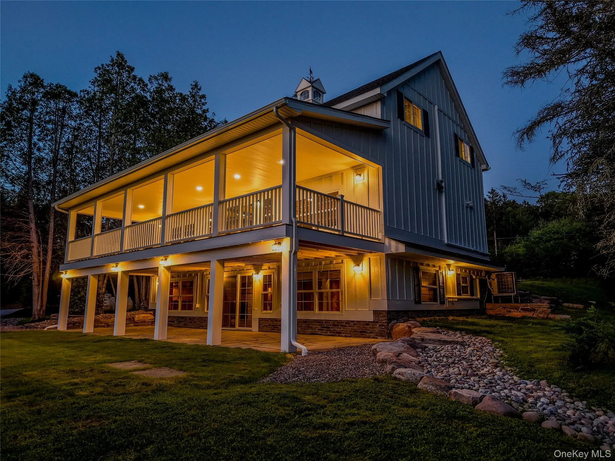 Rear view of house featuring board and batten siding, a yard, stone siding, and a patio Rear view of house featuring board and batten siding, a yard, stone siding, and a patio