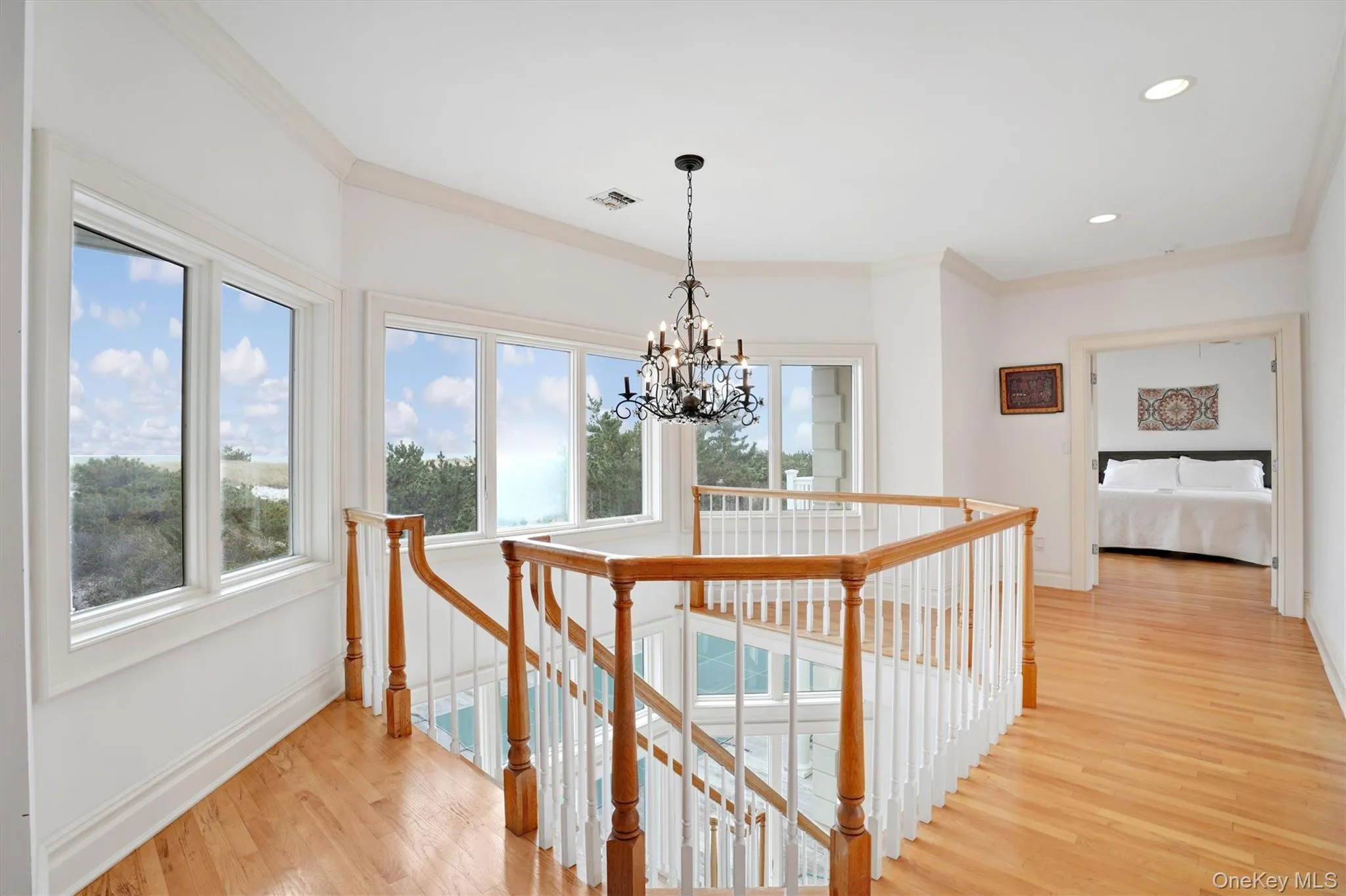 Corridor featuring an upstairs landing, Ocea. views, crown molding, light wood-style flooring, a chandelier, and recessed lighting