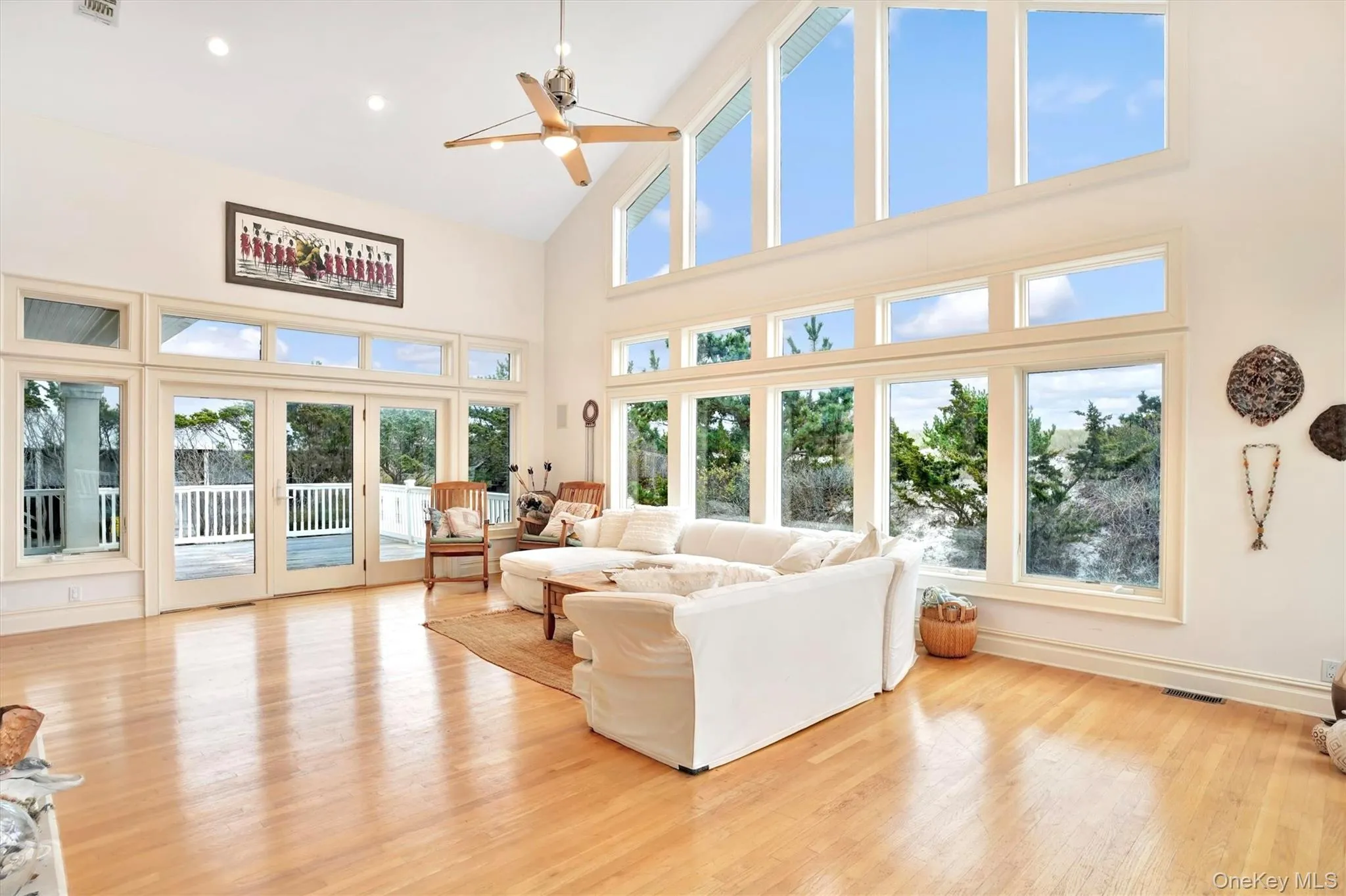 Living area featuring high vaulted ceiling, french doors to two decks, ight wood-style flooring, healthy amount of natural light, a ceiling fan, and recessed lighting
