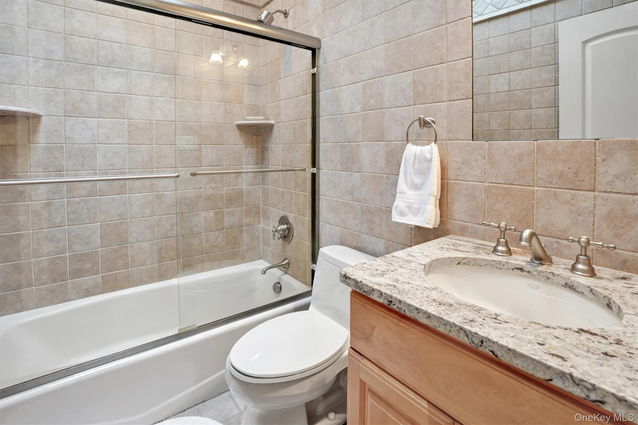 4th Bedroom - ensuite full bathroom with vanity, tile walls, shower / bath combination with glass door, and backsplash