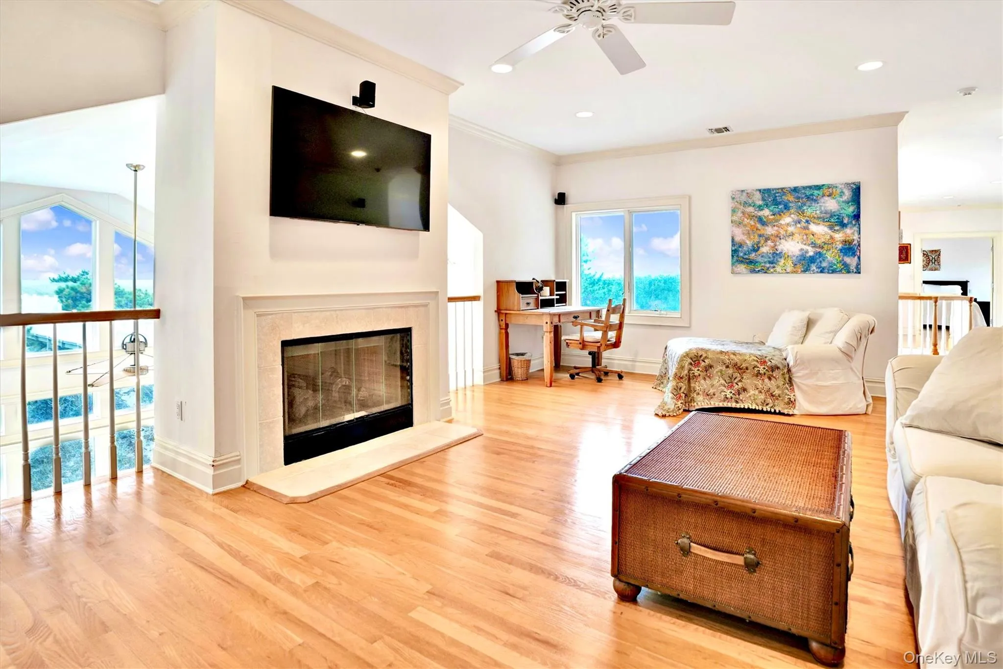 Living area featuring an office area, ornamental molding, light wood-style flooring, a glass covered fireplace, and recessed lighting