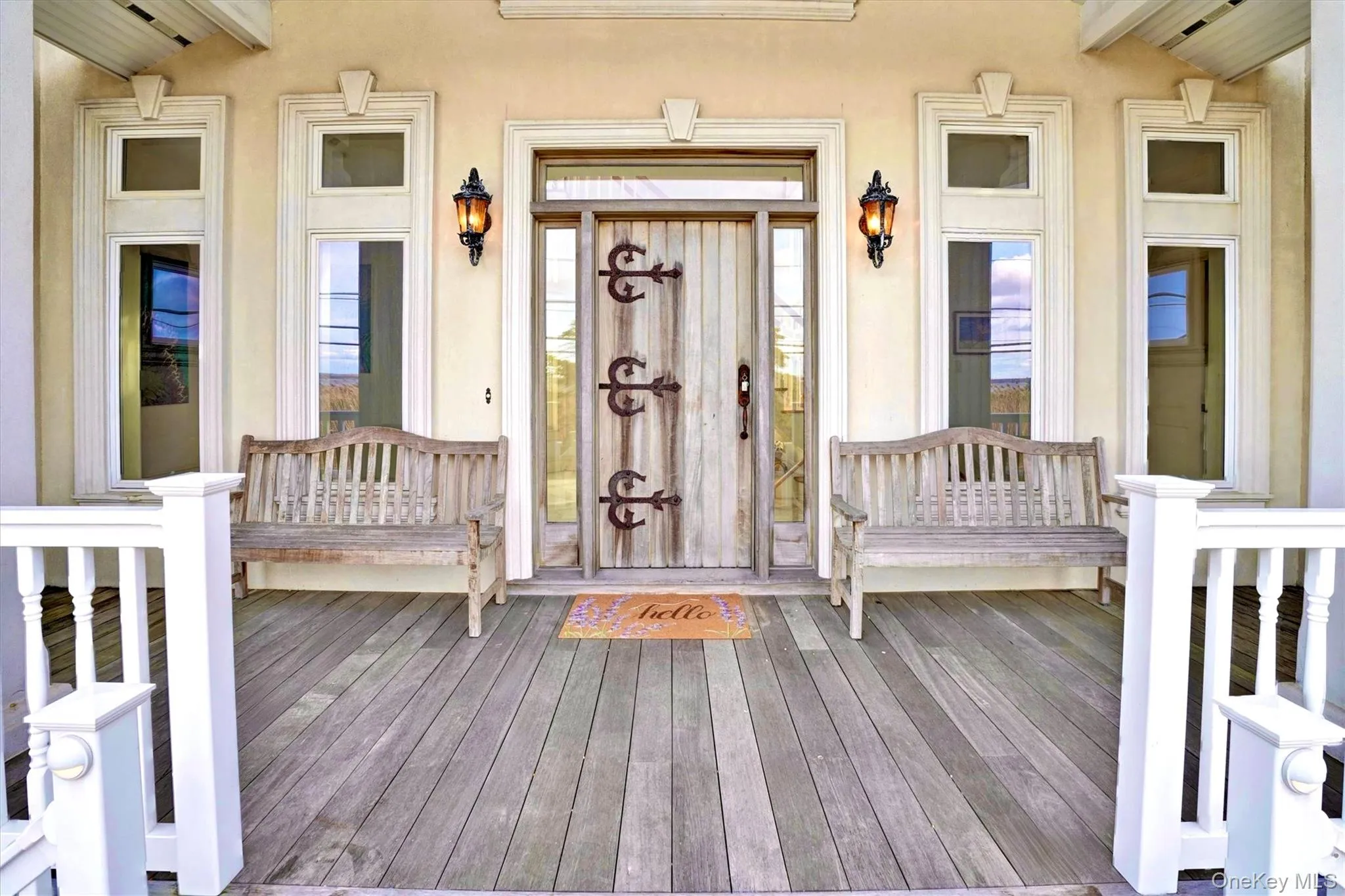 View of exterior entry featuring stucco siding and large mahogany front deck