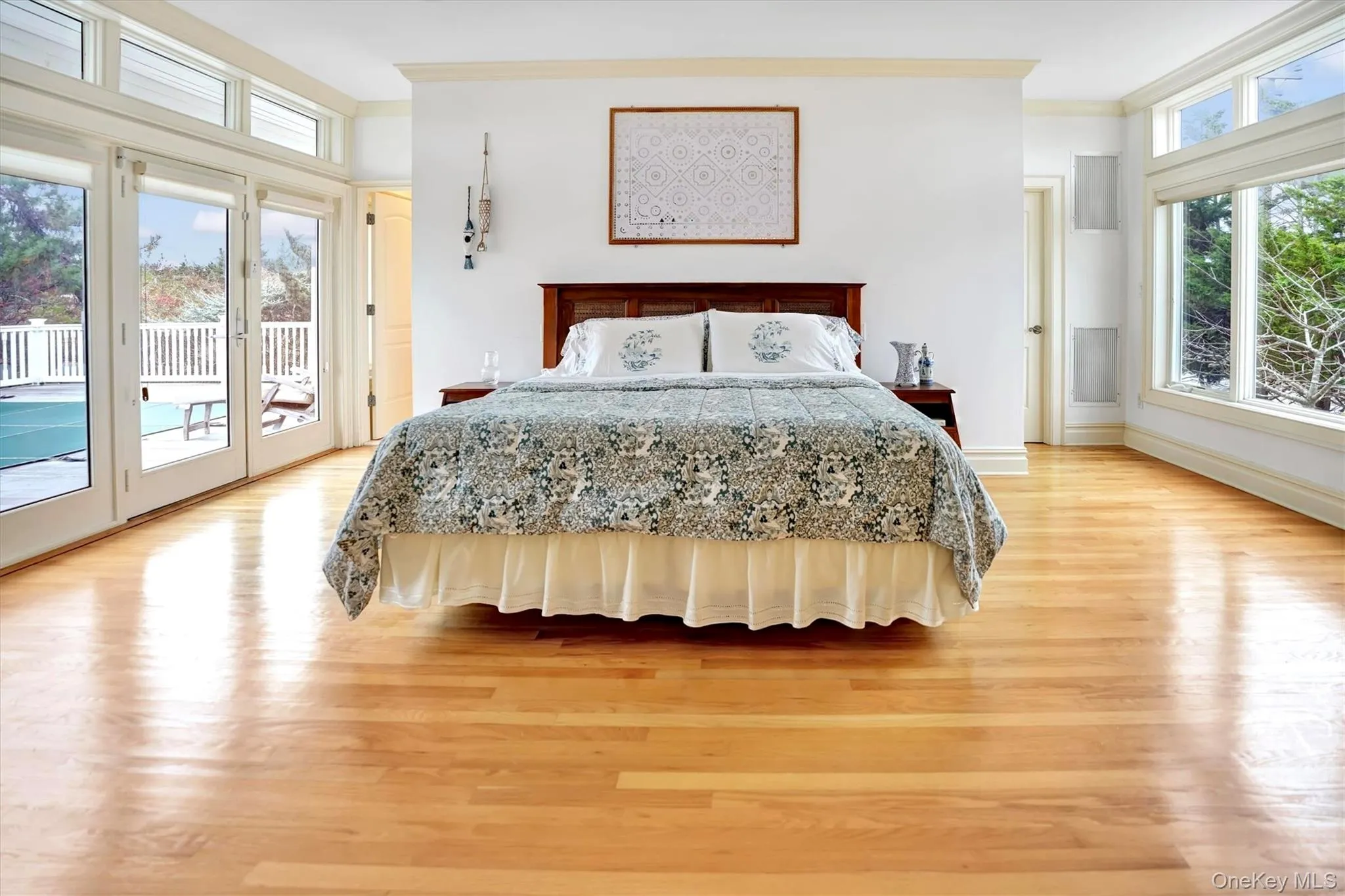 First Floor Primary Bedroom with French Doors to Pool & amazing Bay views. There are wood finished floors, and crown molding.