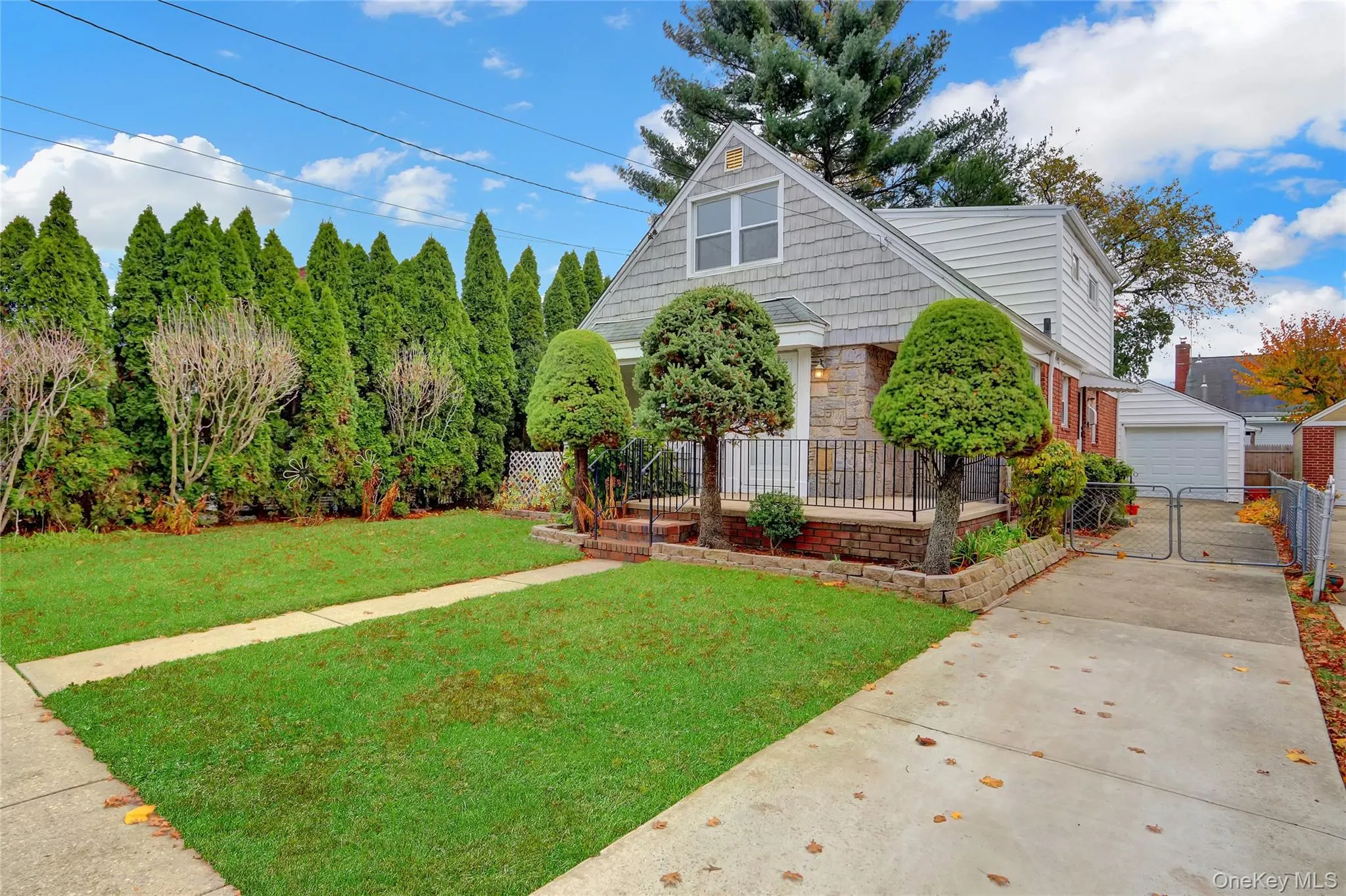 Cape with brick & stone vinyl siding, a gate, and a garage Cape with brick & stone vinyl siding, a gate, and a garage